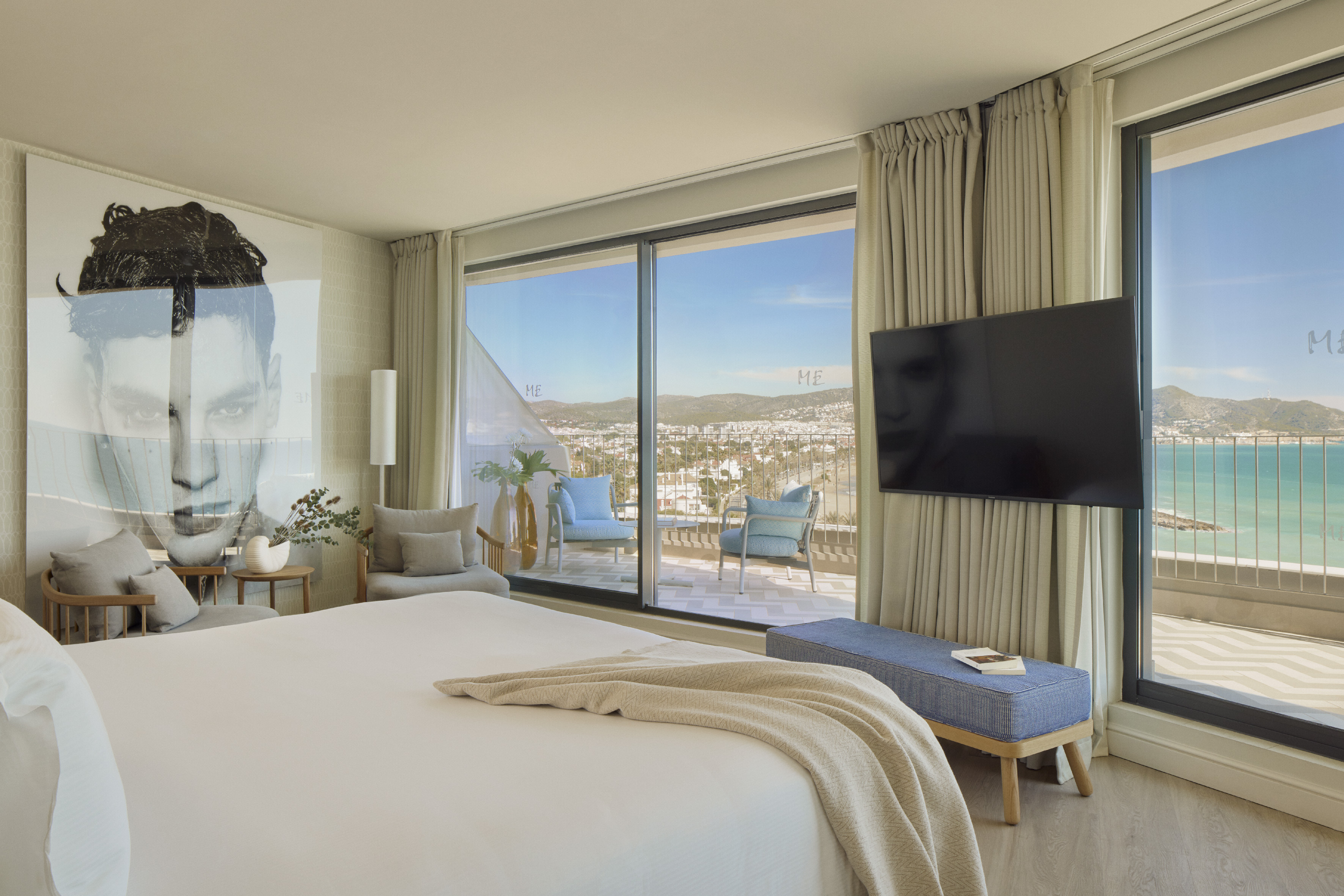 Luxury hotel suite with sea view balcony, king bed, and modern coastal decor.
