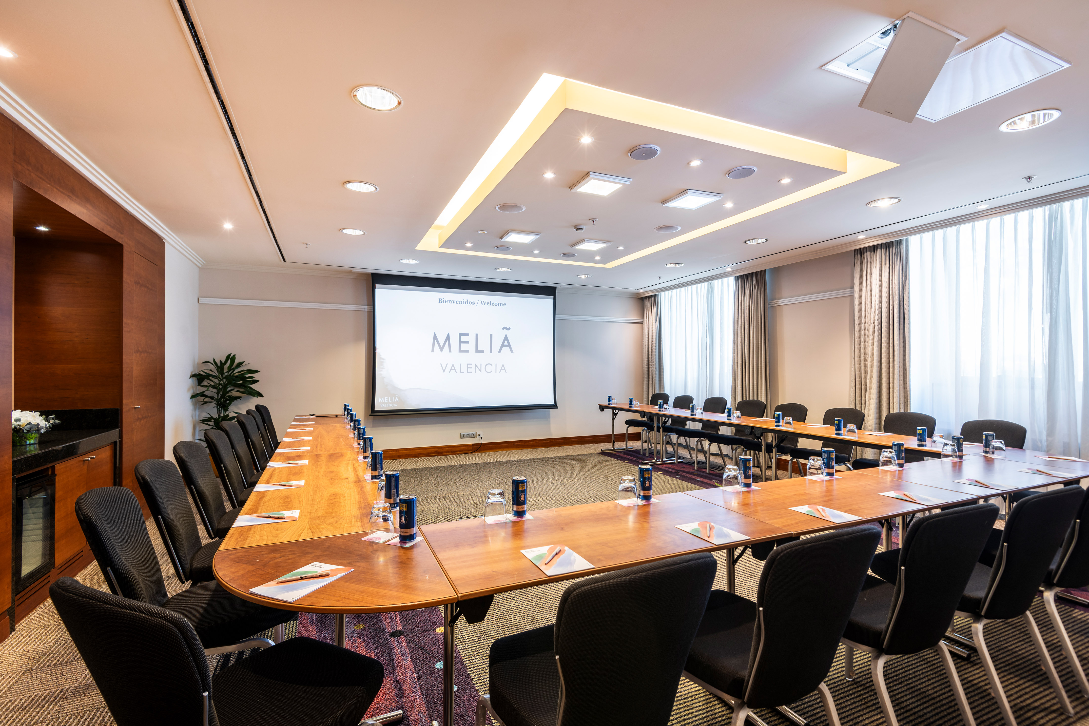 Modern U-shaped conference room at Melia Valencia with projector screen.