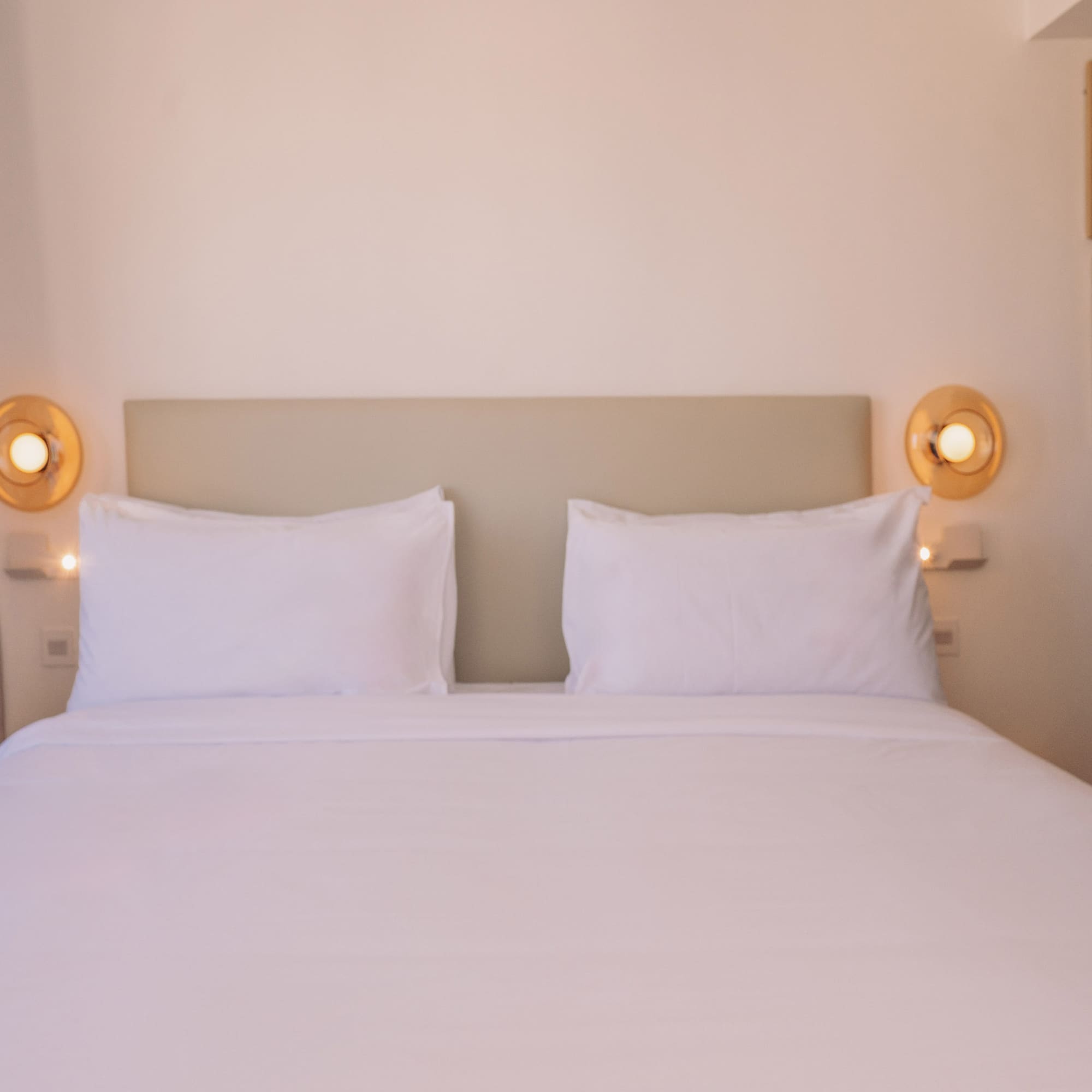 a bed with white sheets and pillows