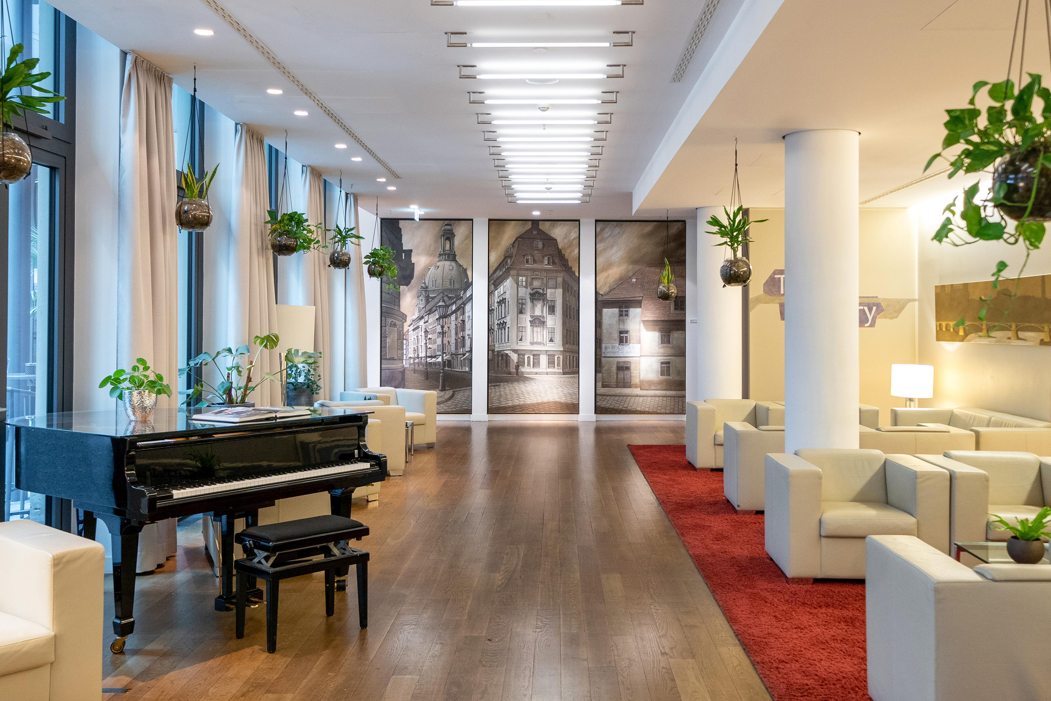 Modern hotel lobby with grand piano, lounge seating, and cityscape artwork.