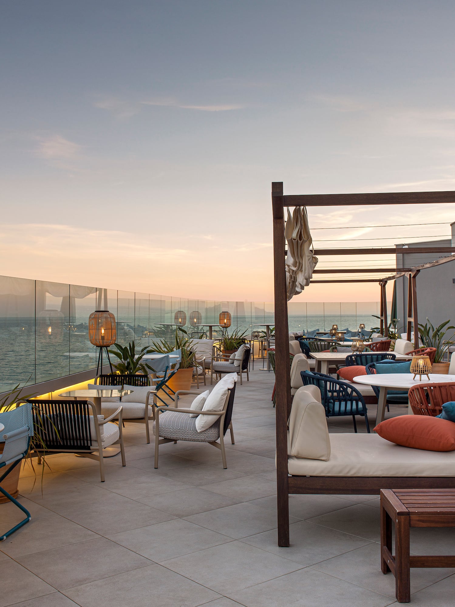 a patio with chairs and tables on a deck overlooking the ocean
