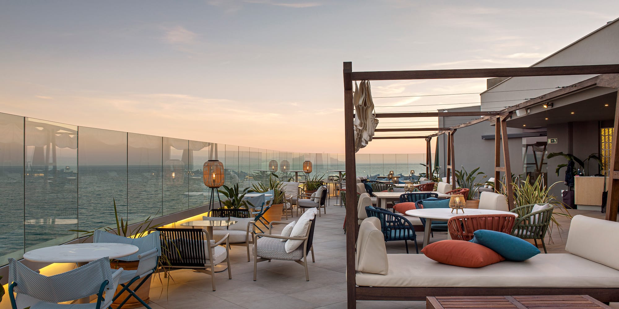 a patio with chairs and tables on a deck overlooking the ocean