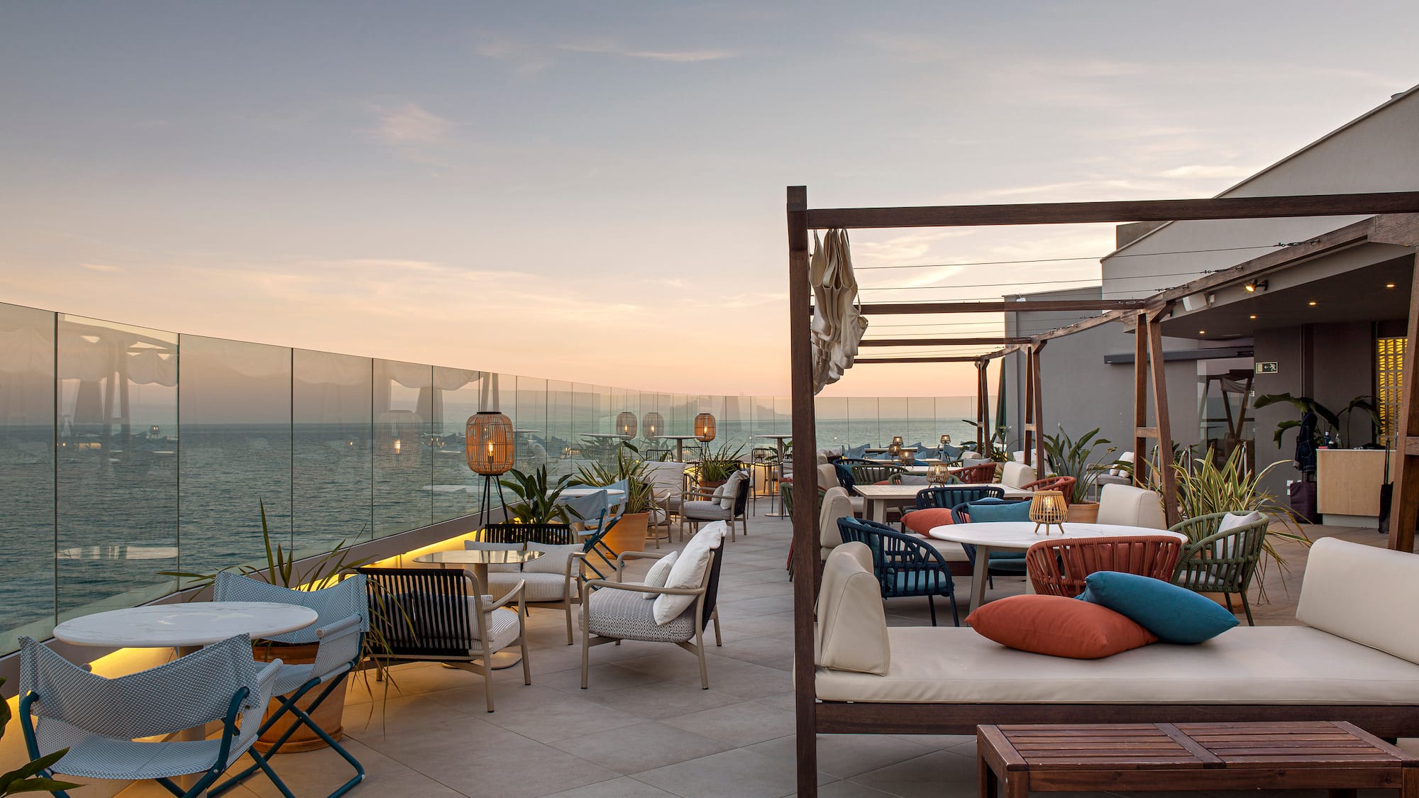 a patio with chairs and tables on a deck overlooking the ocean