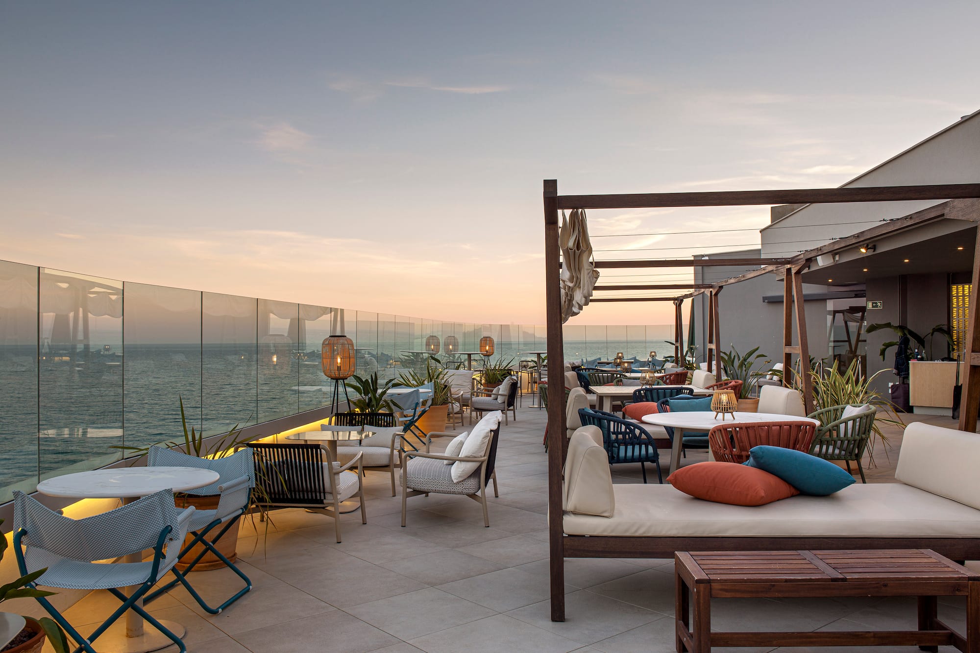 a patio with chairs and tables on a deck overlooking the ocean