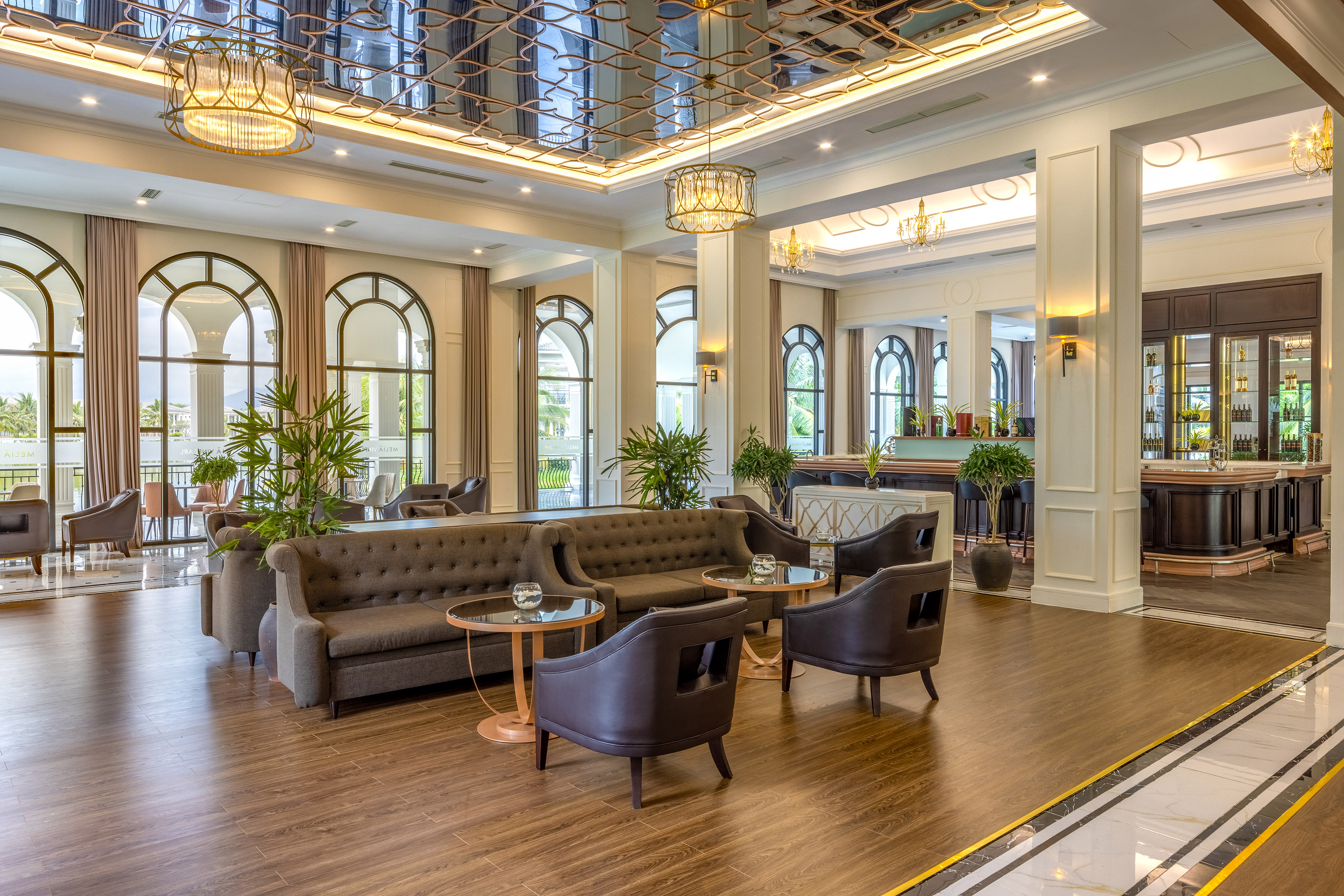 Luxurious resort lobby with elegant seating, arched windows, and mirrored ceiling.