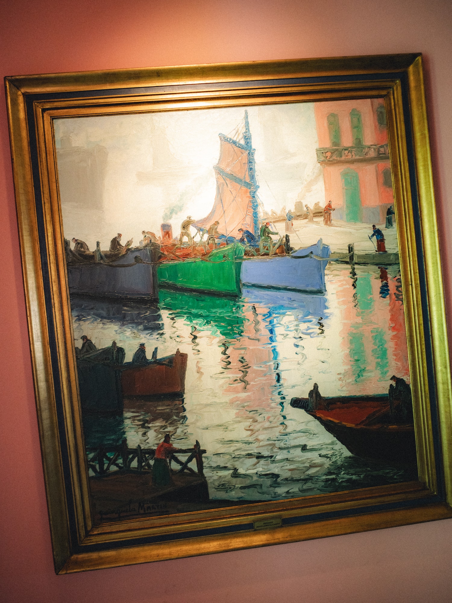 Pintura de barcos coloridos en puerto, con reflejos y marco dorado.
