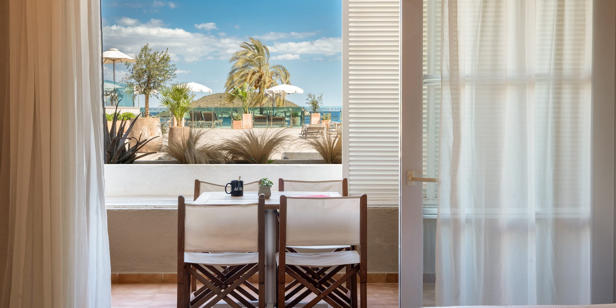 a room with a table and chairs and a bed and a window