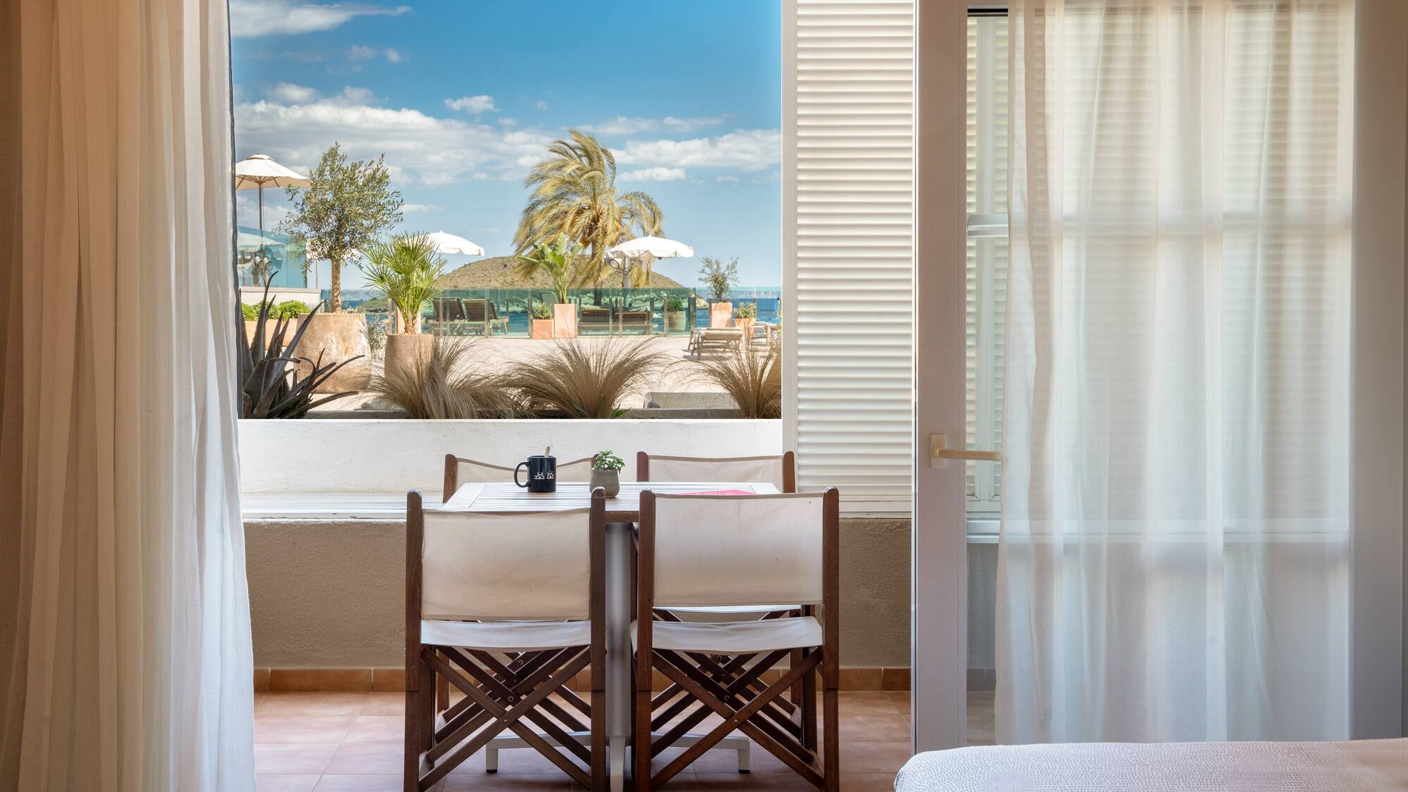 a room with a table and chairs and a bed and a window