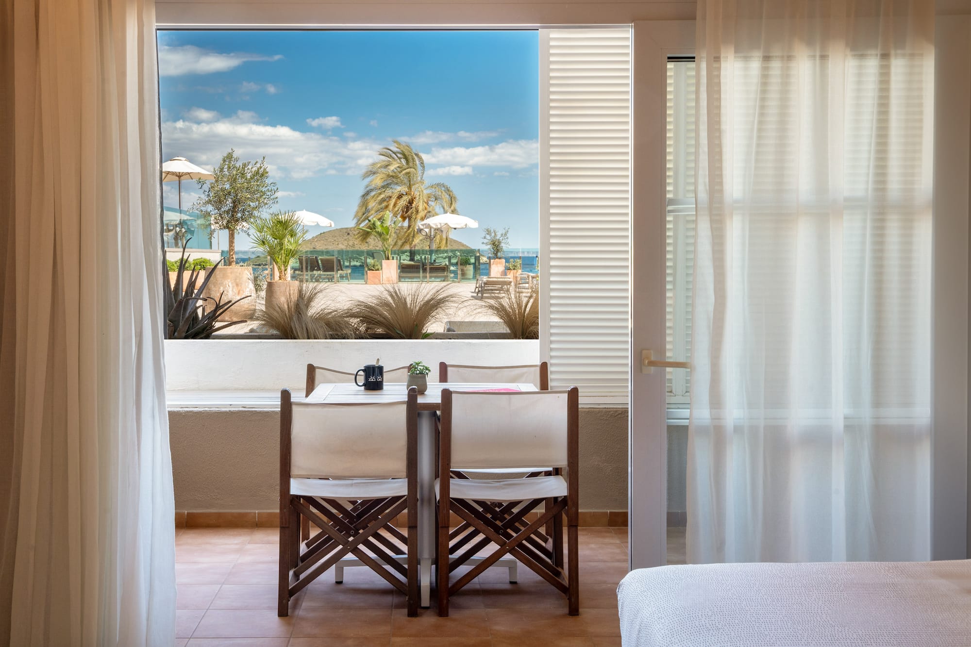 a room with a table and chairs and a bed and a window