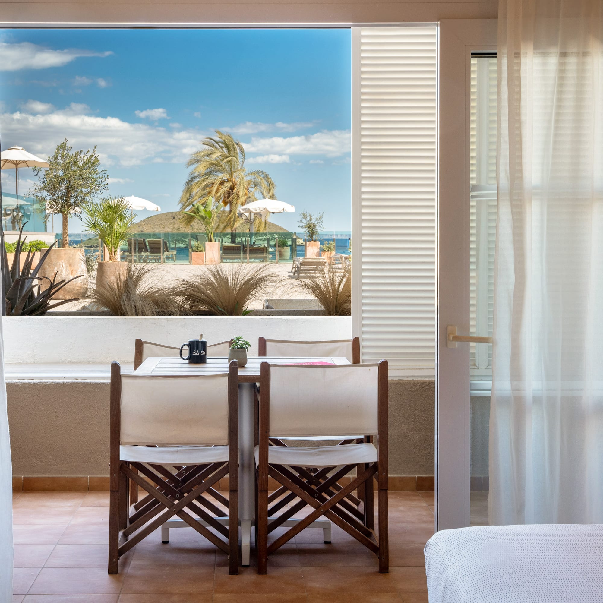 a room with a table and chairs and a bed and a window