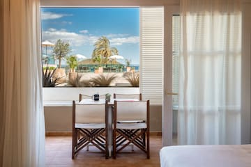 a room with a table and chairs and a bed and a window