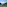 Balcony view of a turquoise bay, pine trees, and wooded Mediterranean coast.
