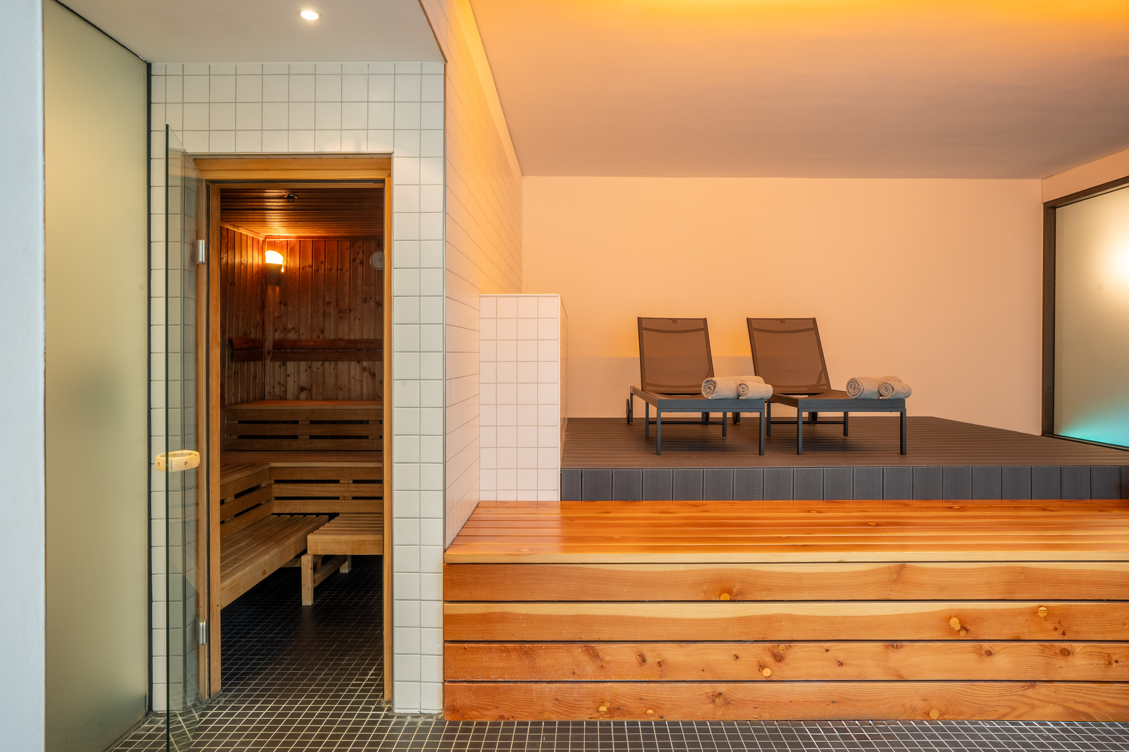 Hotel spa sauna with wooden benches and adjacent relaxation lounge chairs. - Centre de bien-être - INNSiDE Düsseldorf Seestern, Düsseldorf