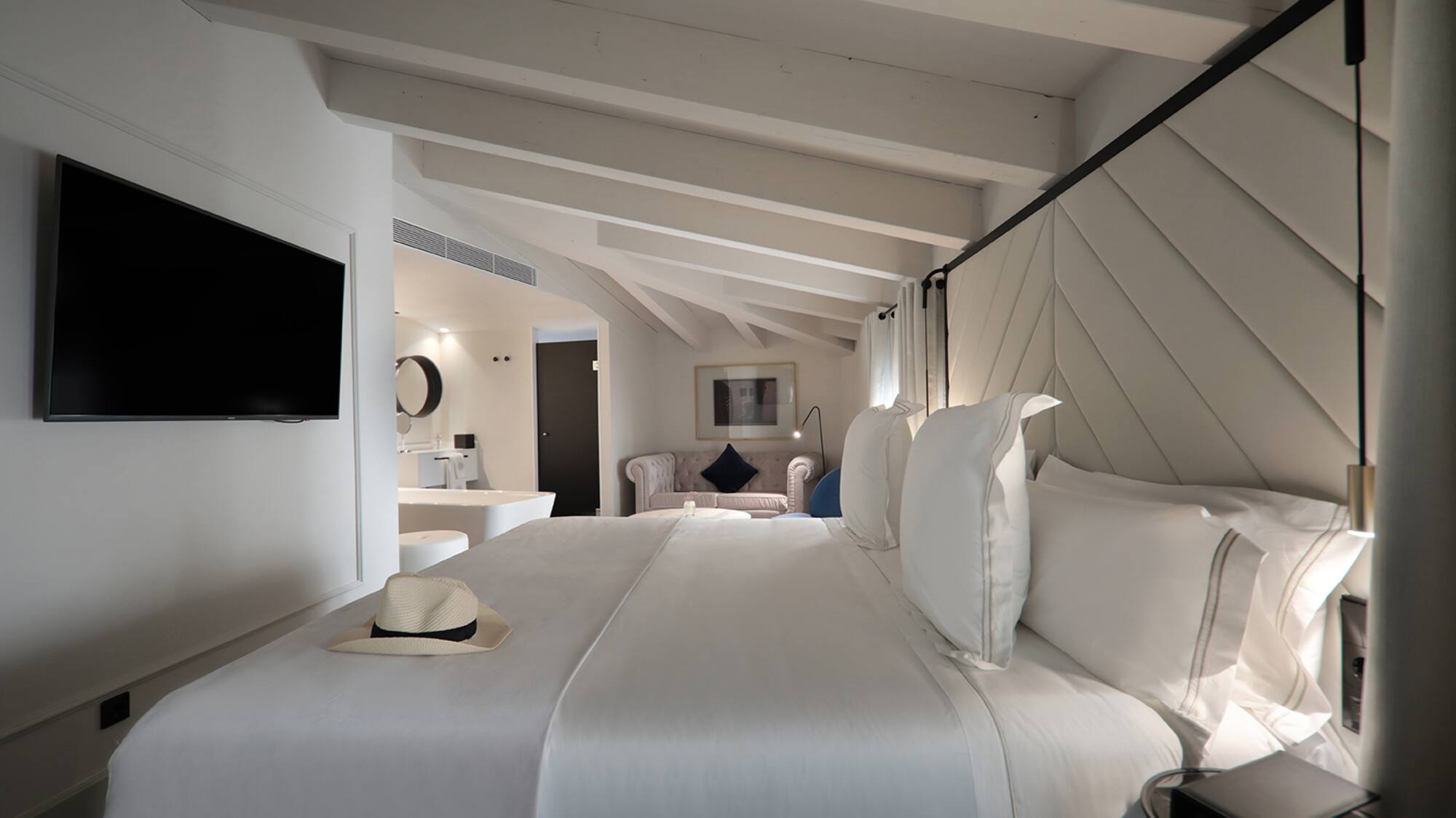 a bed with white sheets and a hat on it