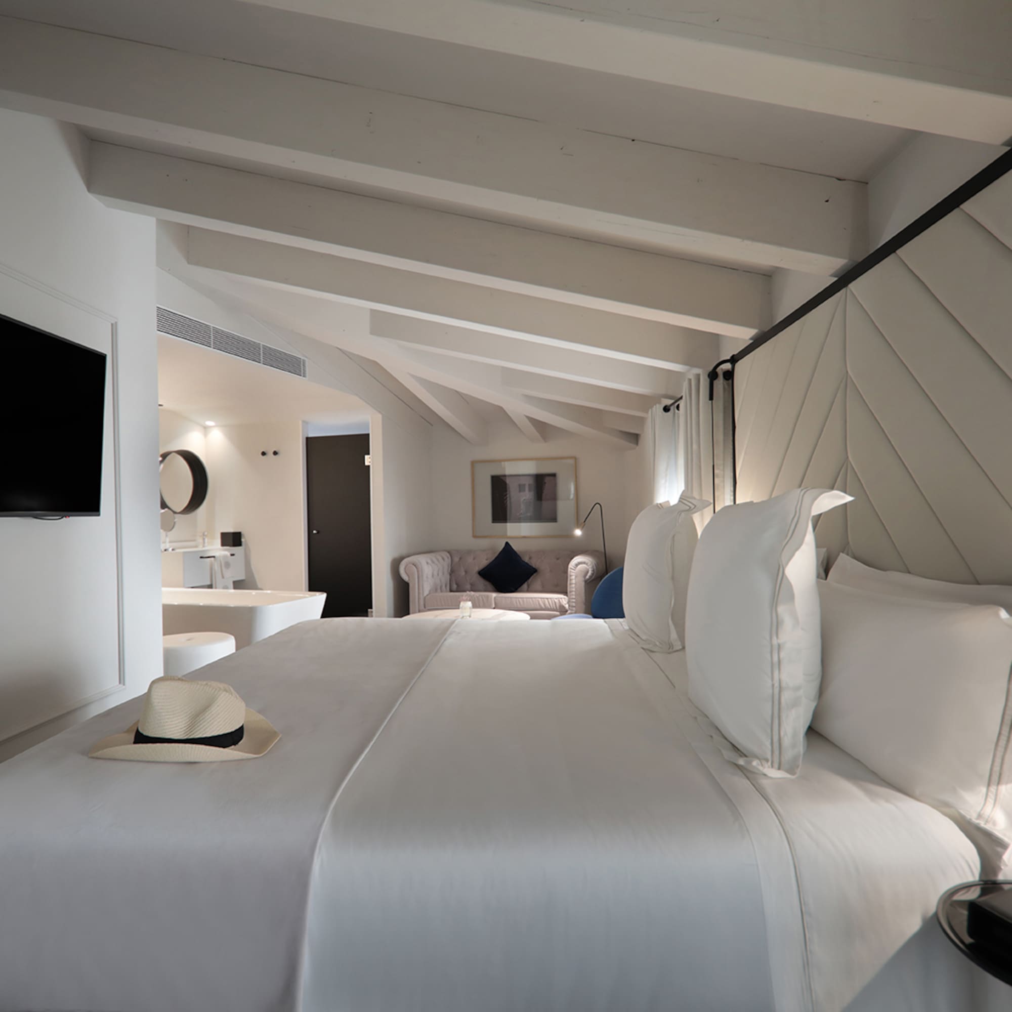 a bed with white sheets and a hat on it