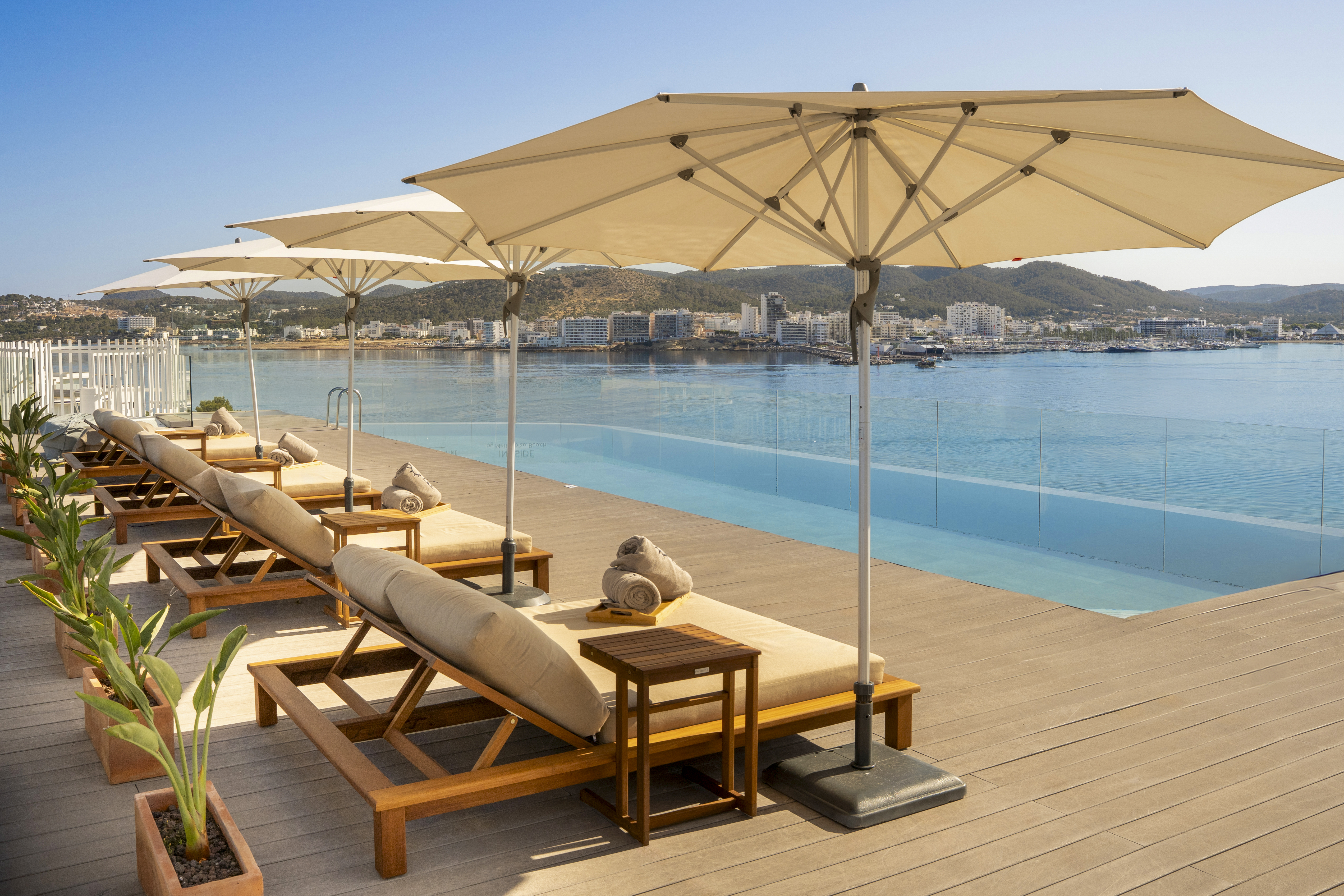 Hotel infinity pool terrace with lounge chairs, umbrellas, and bay view.