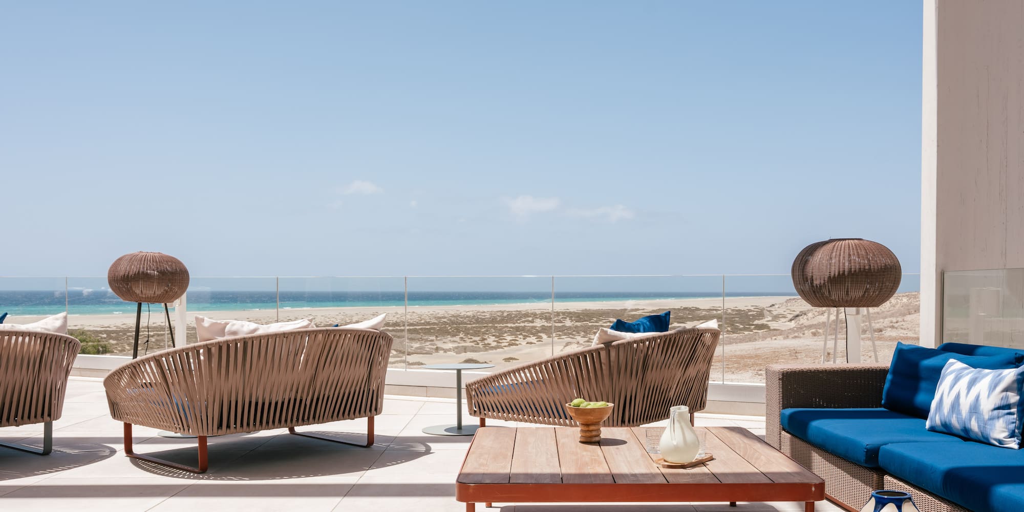 Outdoor lounge terrace with ocean view and modern wicker furniture.
