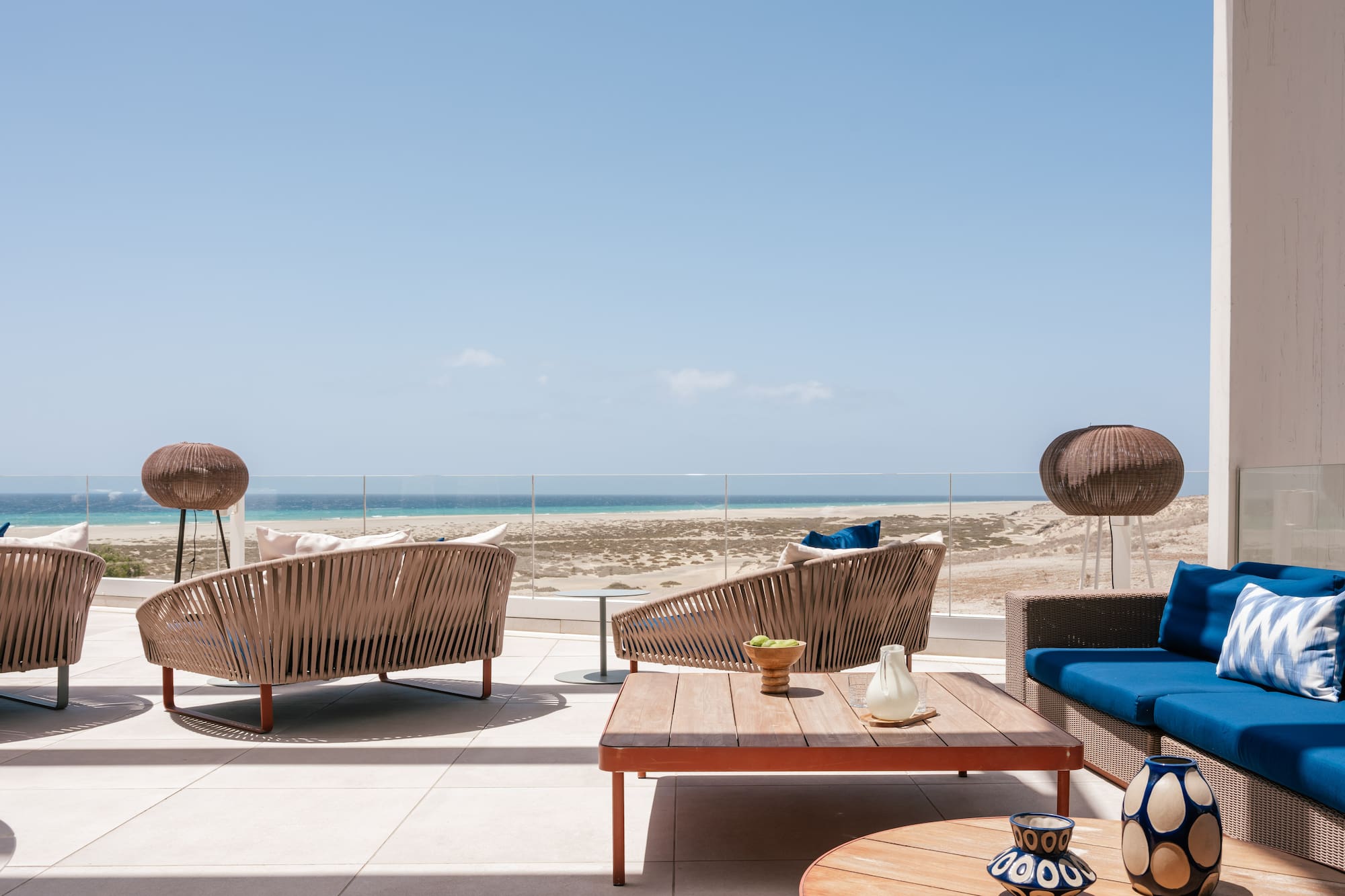 Outdoor lounge terrace with ocean view and modern wicker furniture.