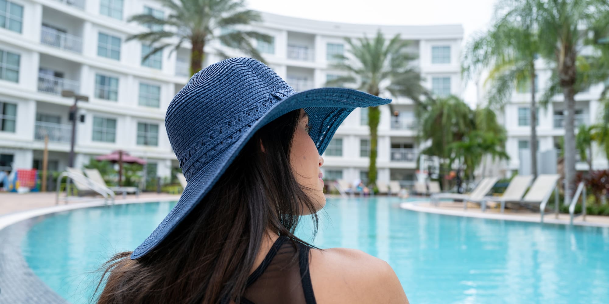 a woman wearing a hat by a pool