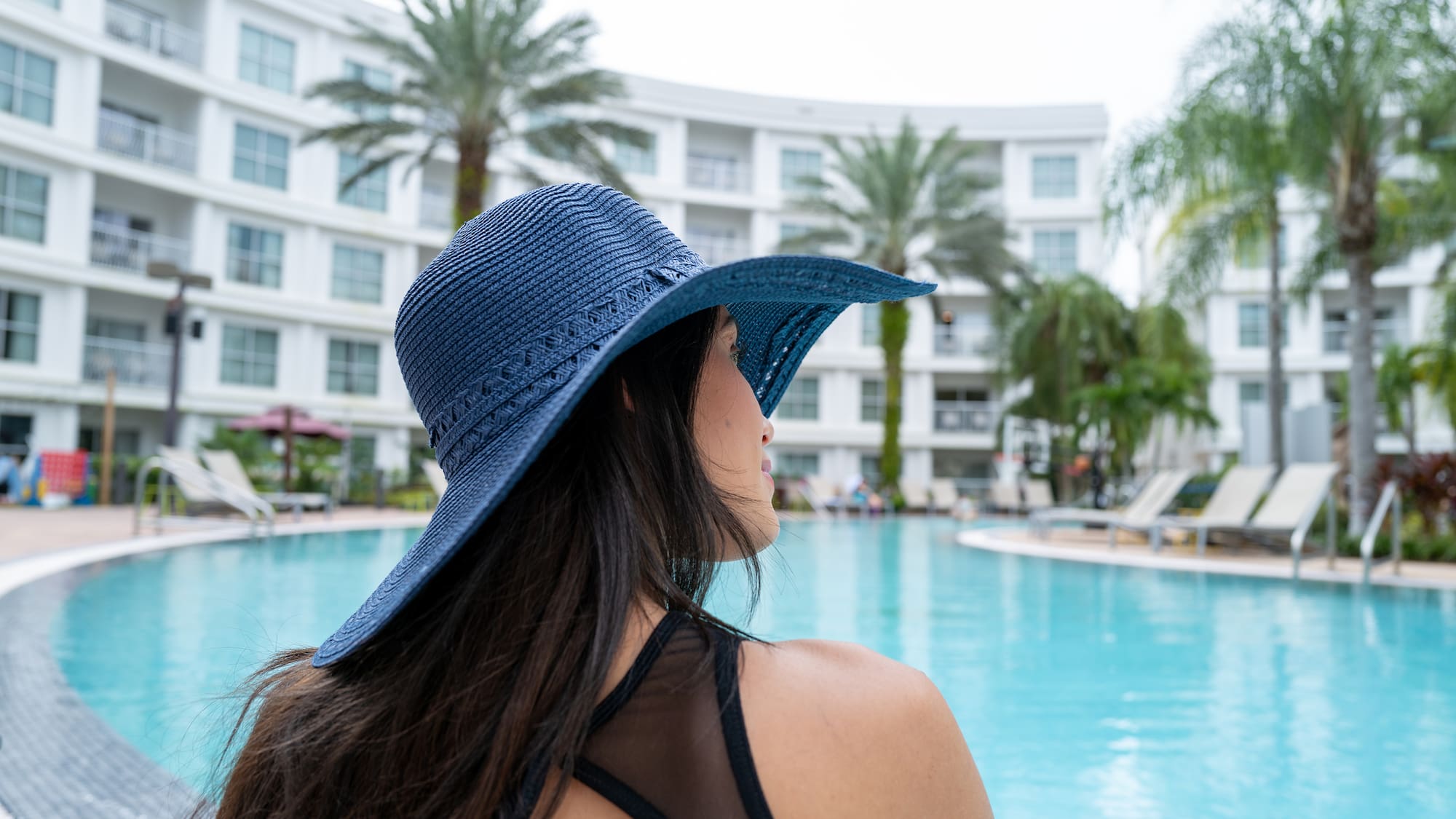 a woman wearing a hat by a pool