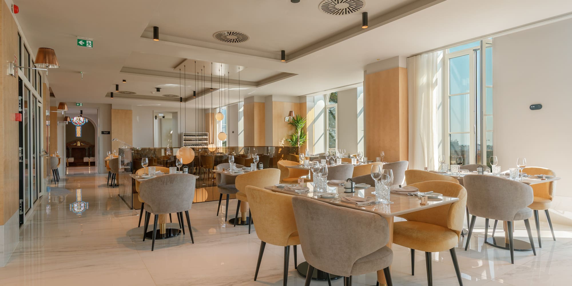 Modern elegant restaurant interior with set tables, grey and yellow chairs.