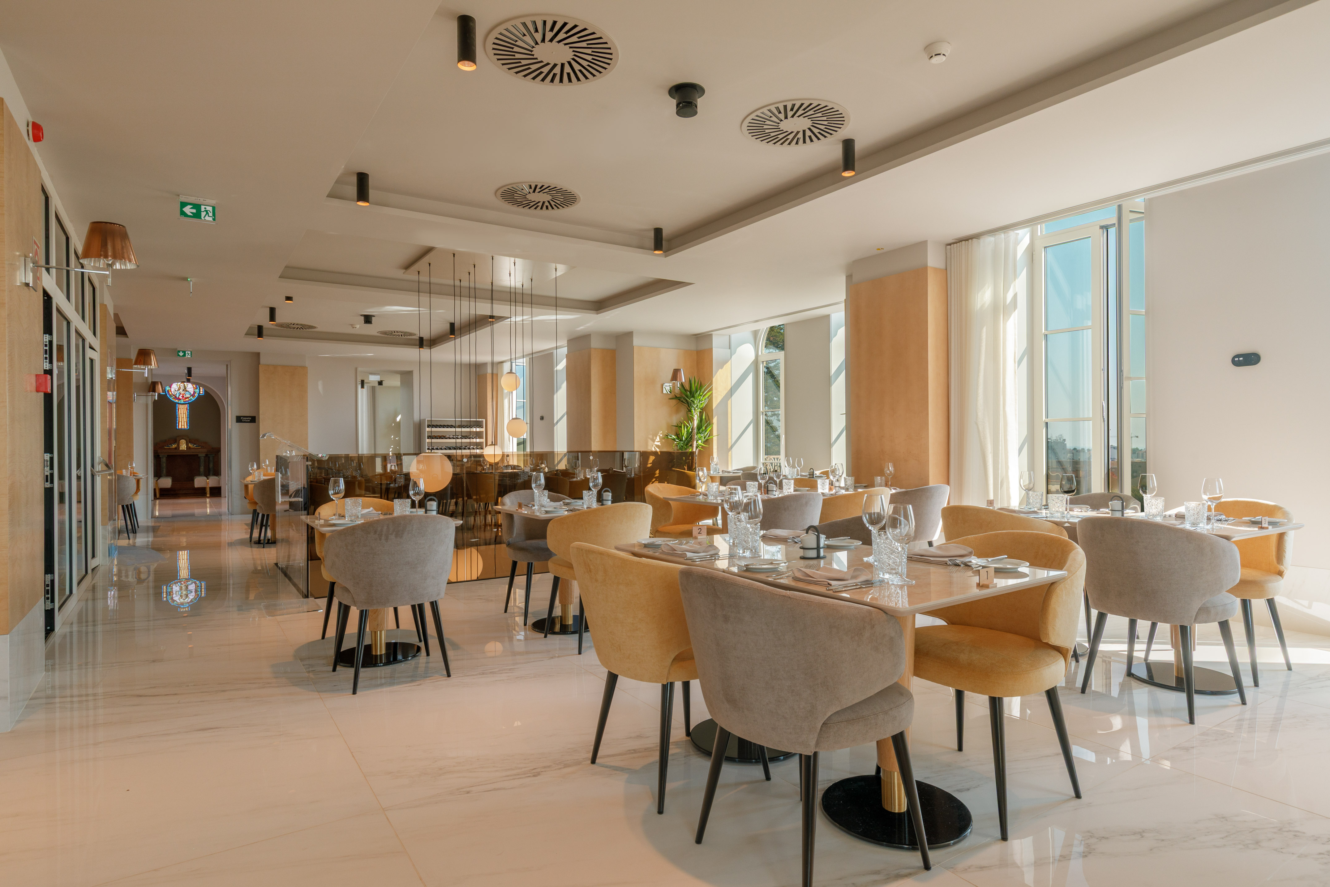 Modern elegant restaurant interior with set tables, grey and yellow chairs.