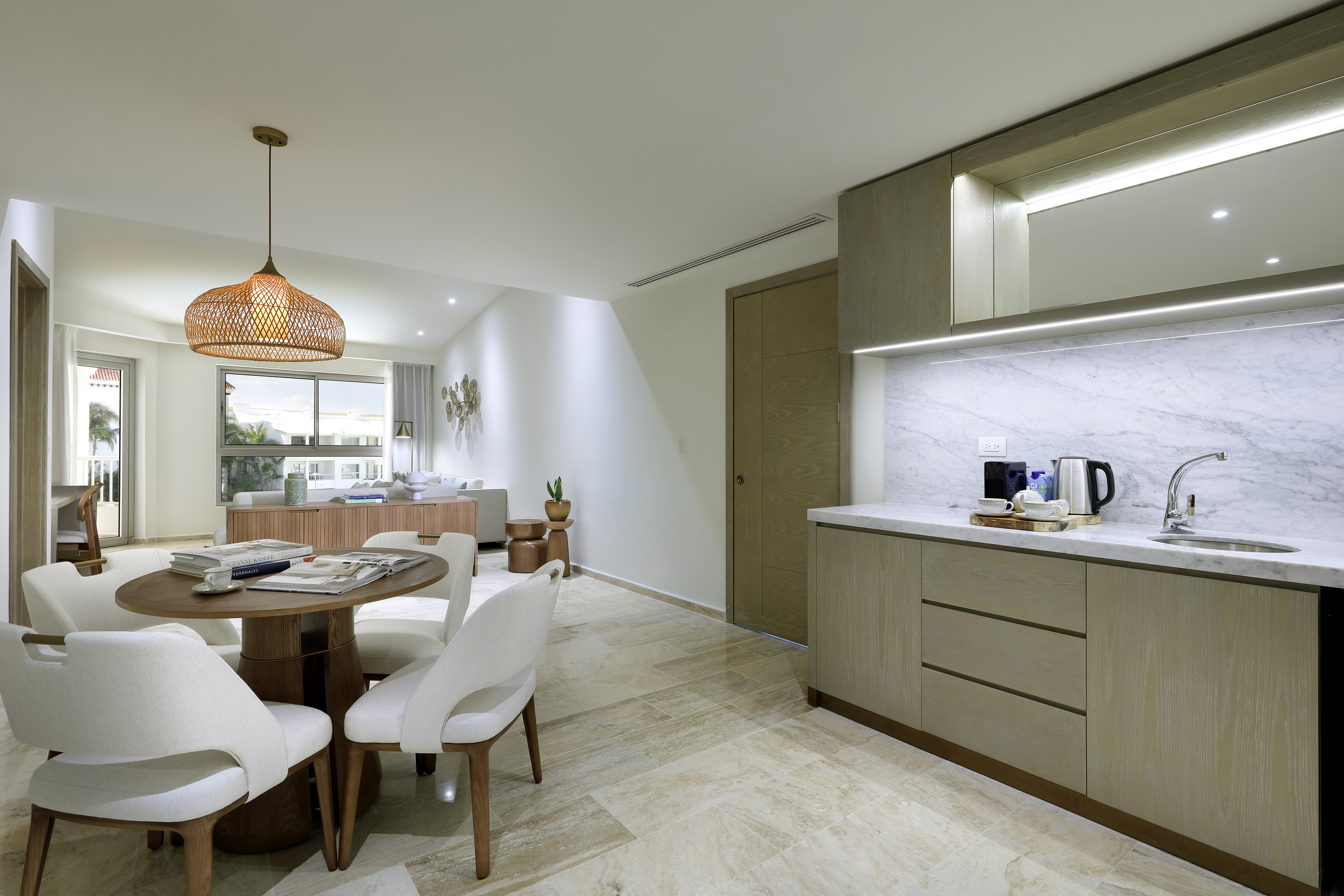 Open-plan living with modern kitchen, dining area, and rattan pendant light.