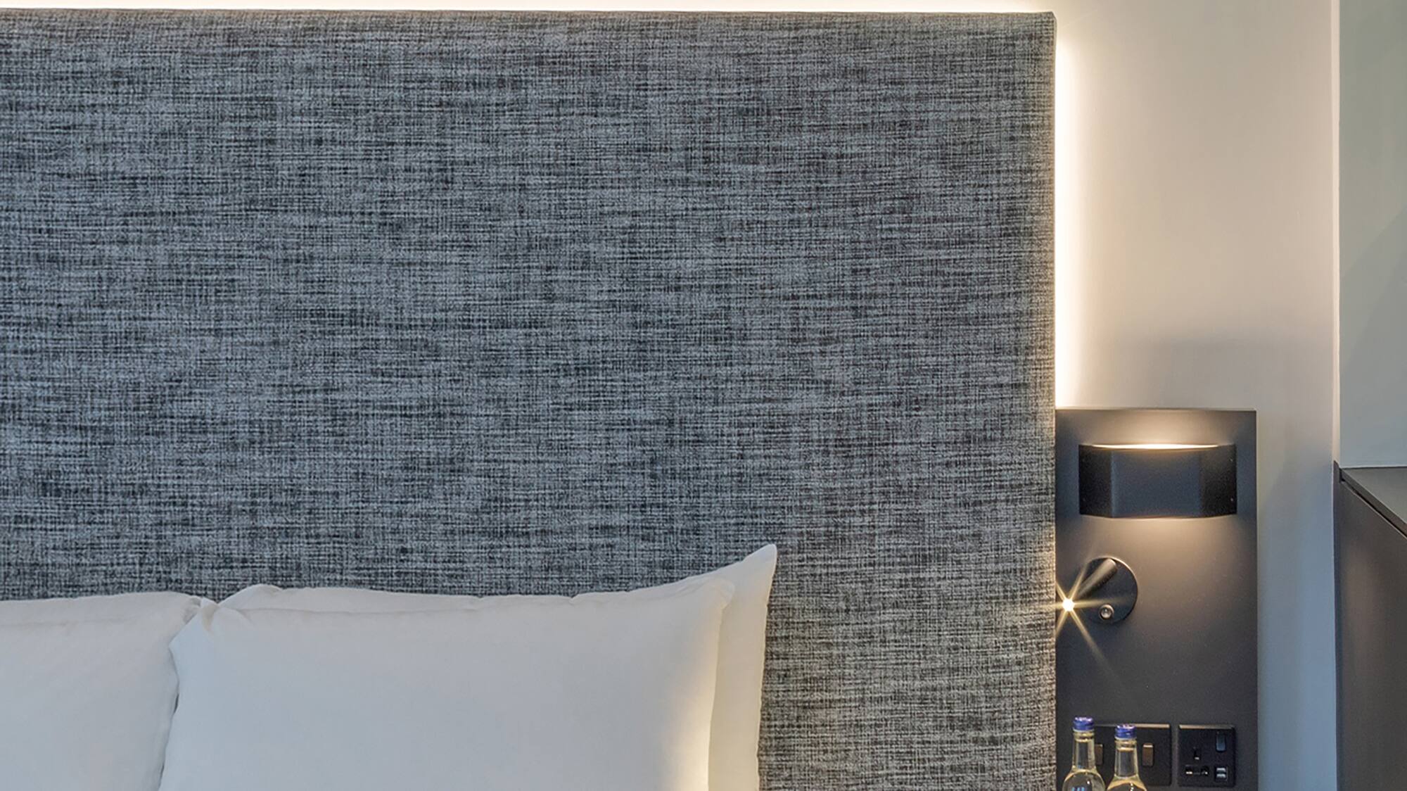 a bed with a table and two bottles of water on it