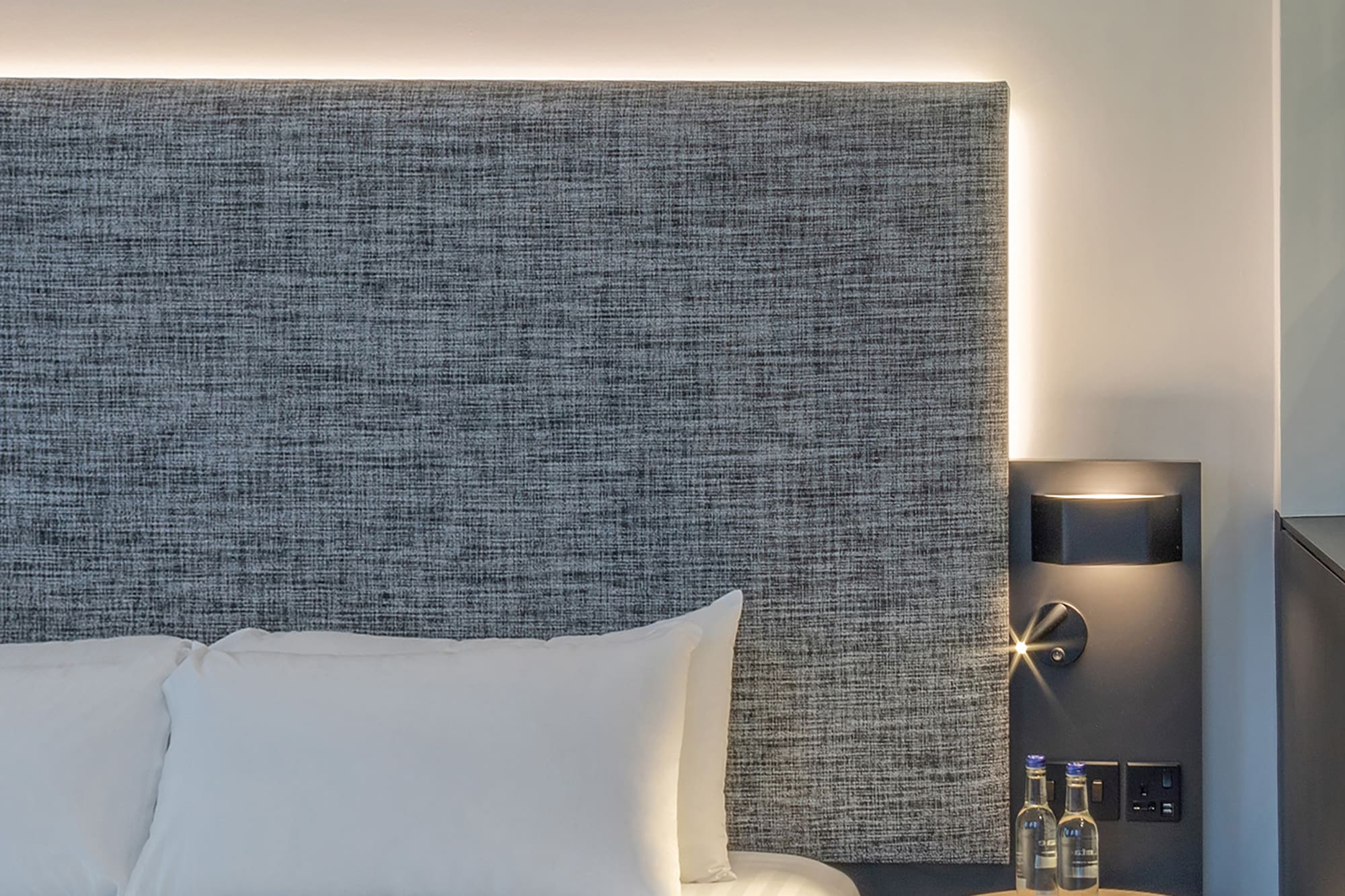 a bed with a table and two bottles of water on it