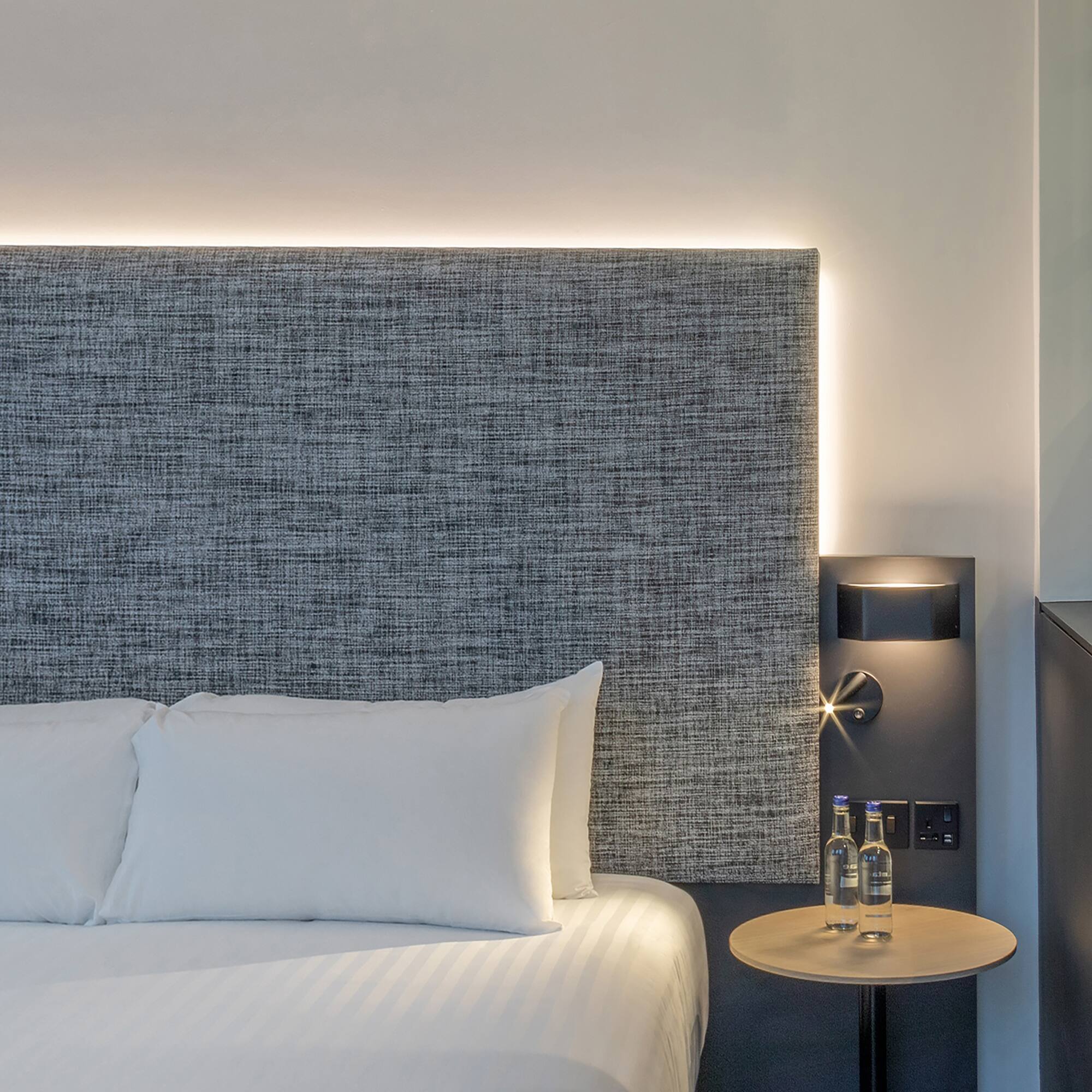 a bed with a table and two bottles of water on it