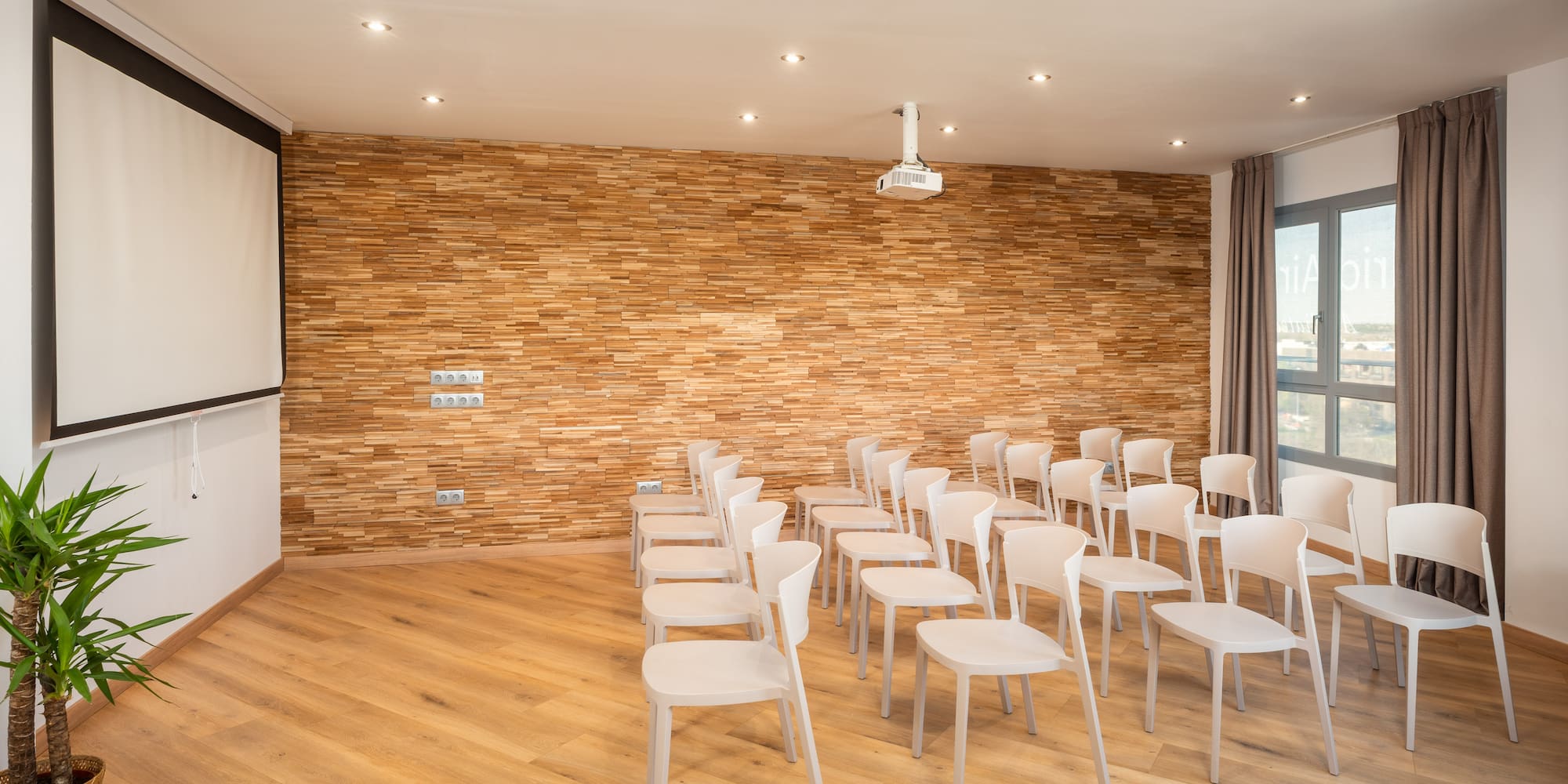 a room with white chairs and a projector screen
