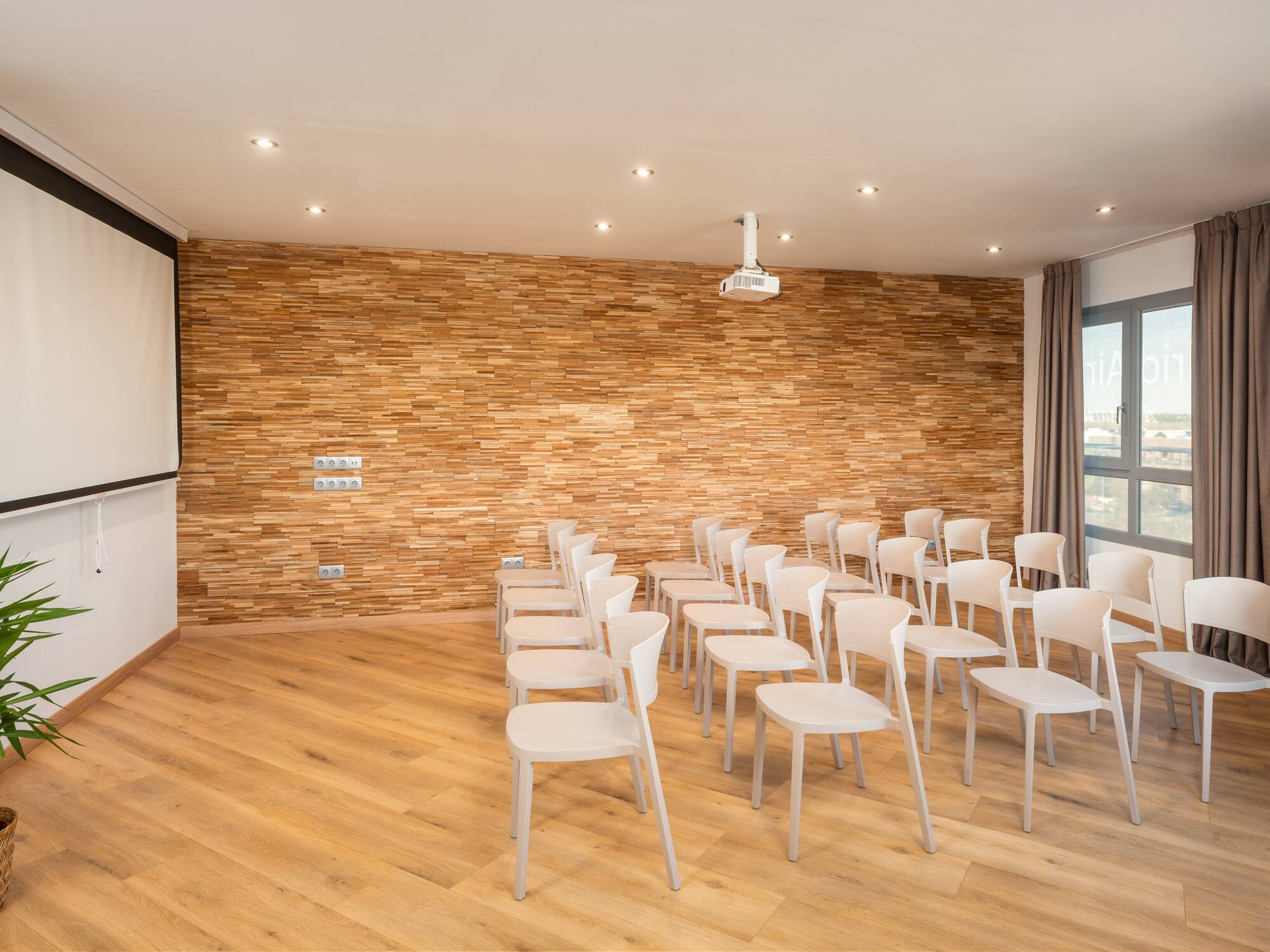 a room with white chairs and a projector screen