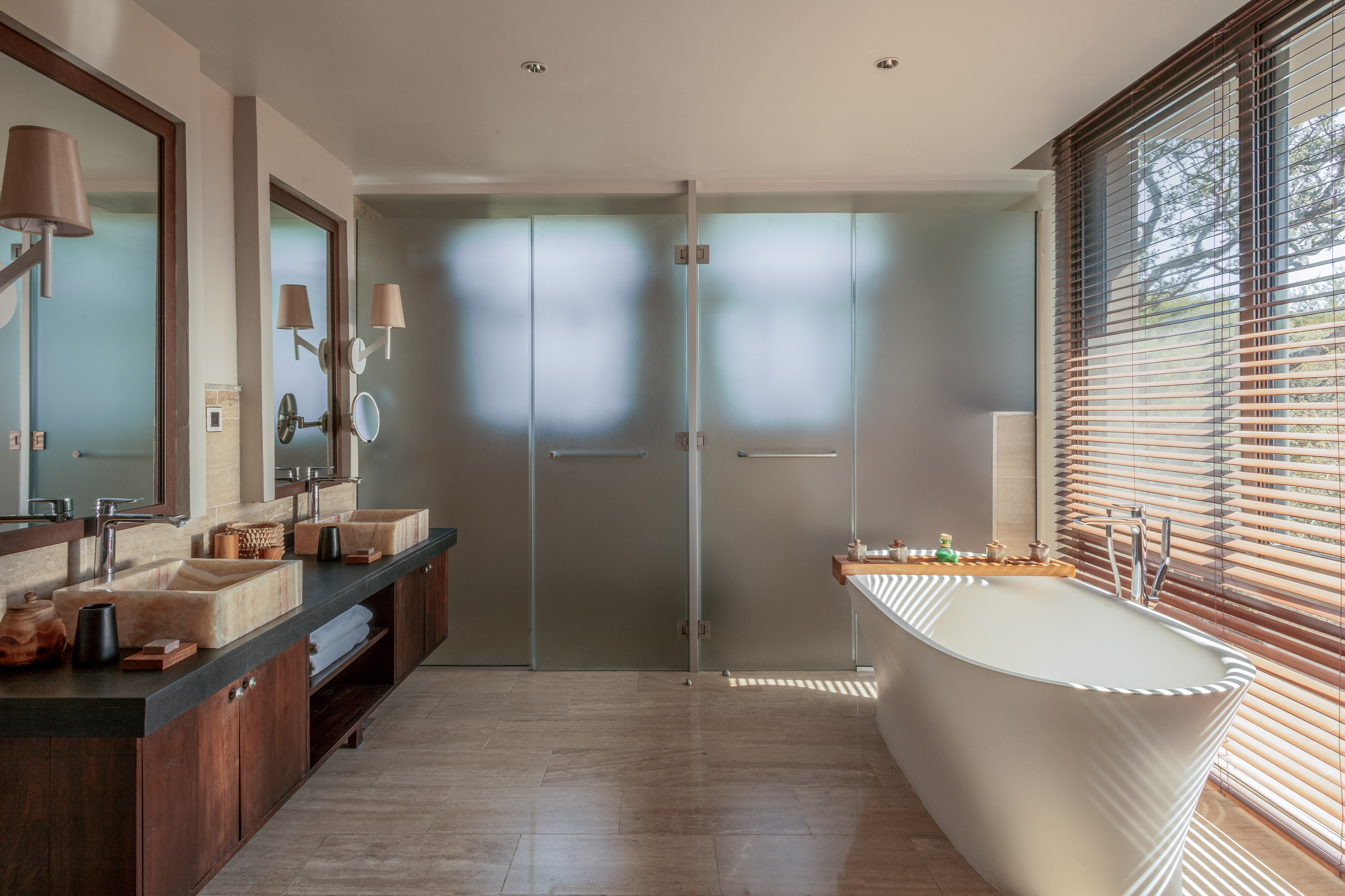 Spacious modern bathroom with double stone vanity, freestanding tub, glass shower.