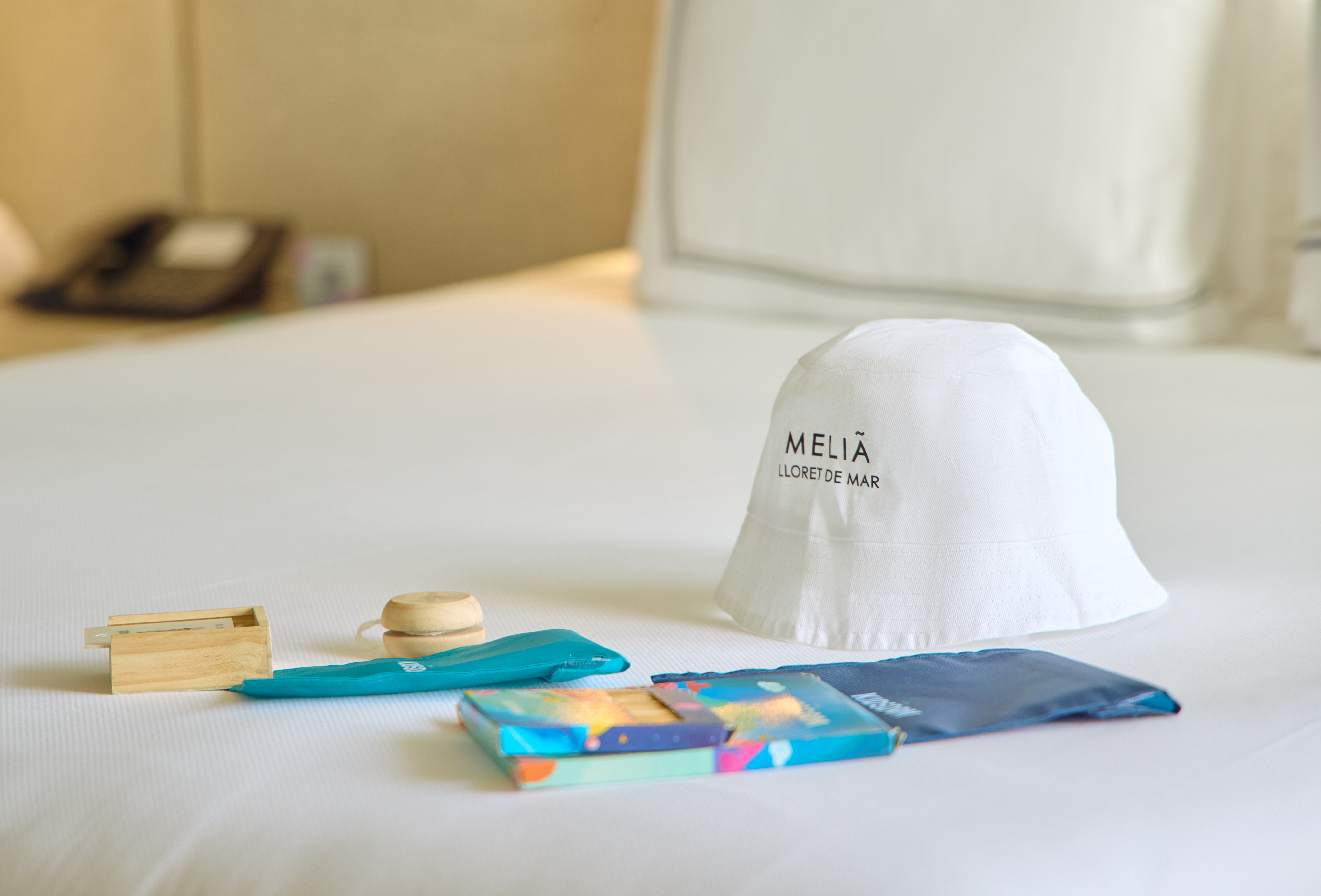 Meliã Lloret de Mar hotel welcome kit: bucket hat, wooden toy, and art supplies.