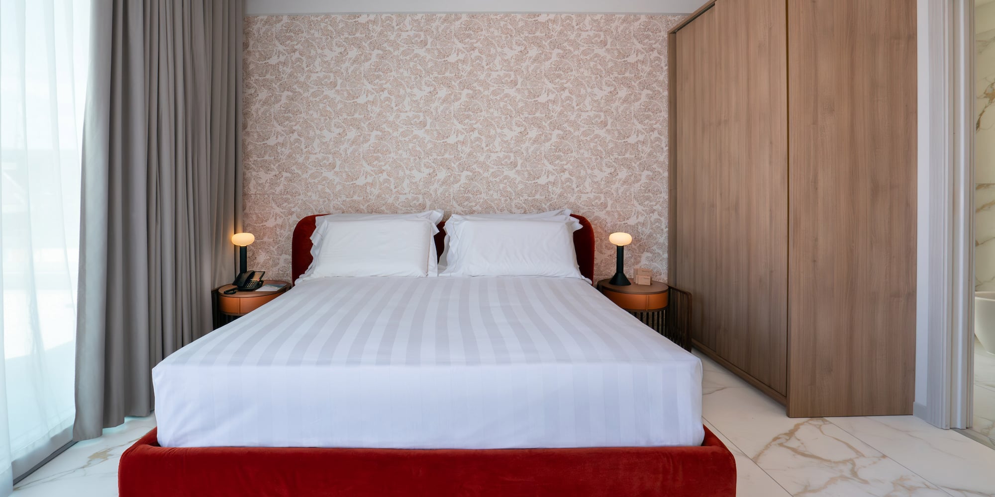 a bed with a red bed frame and a wood cabinet