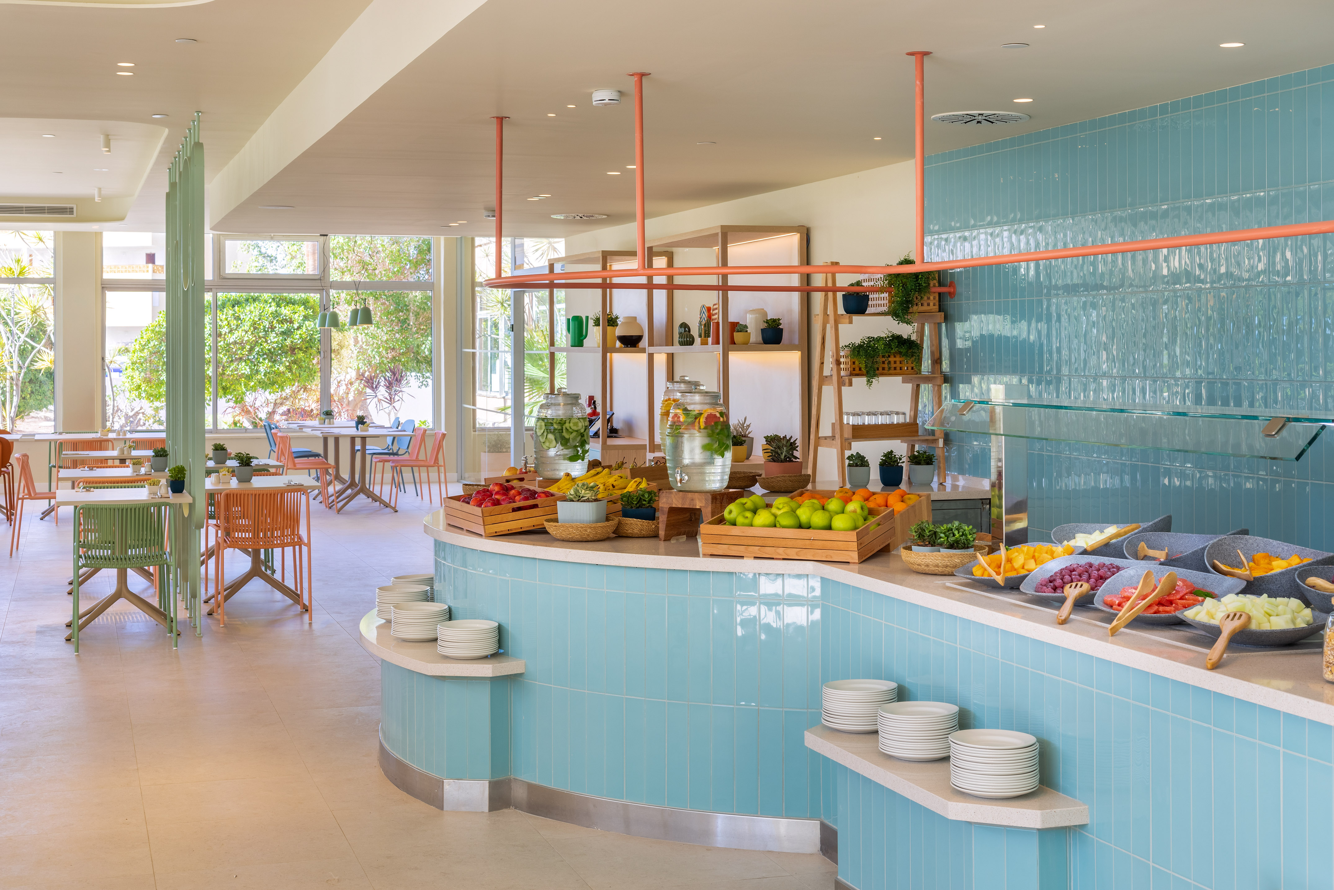Hotel buffet breakfast with fresh fruit, healthy drinks, and modern dining area.