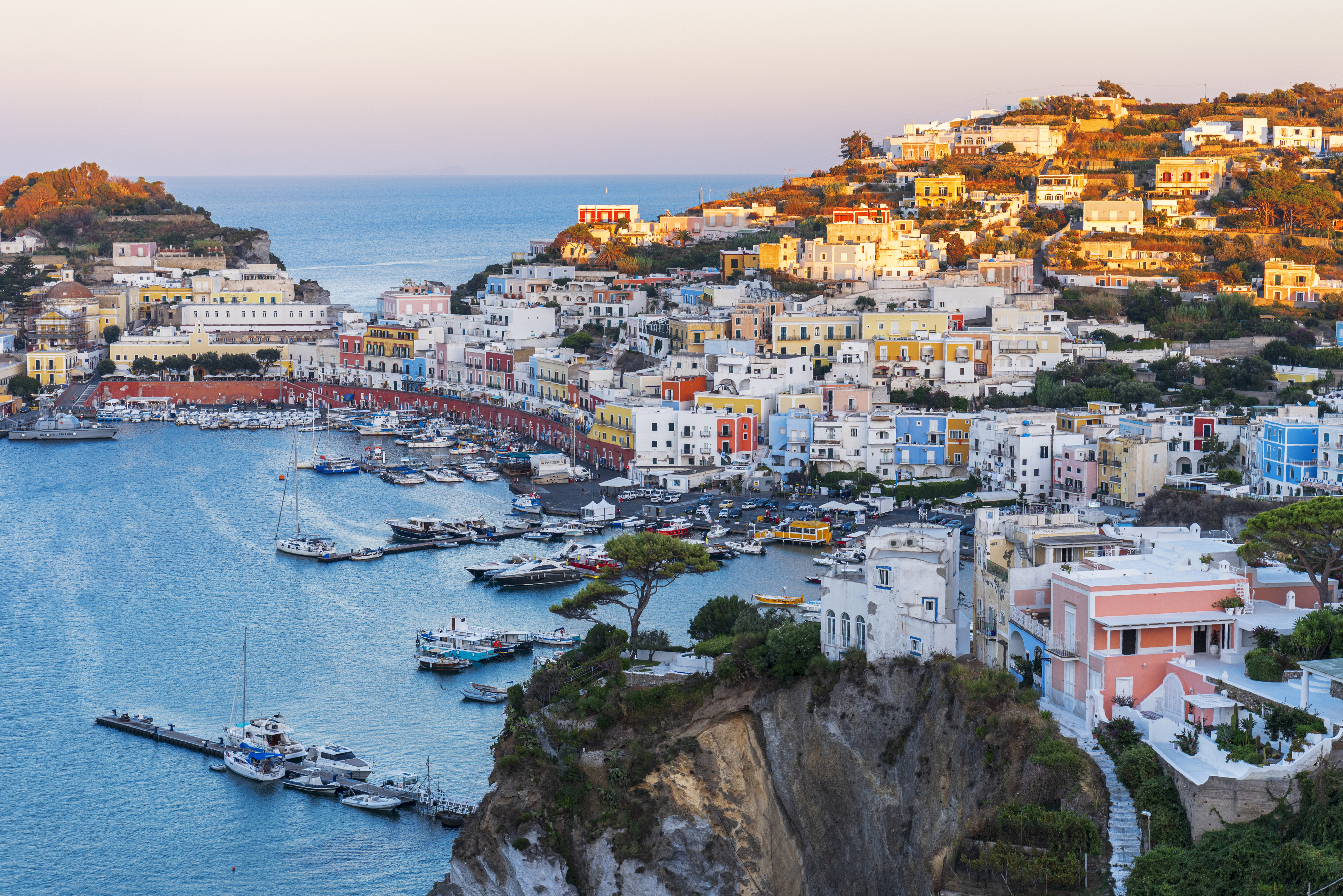 a city on a hill with boats on the water