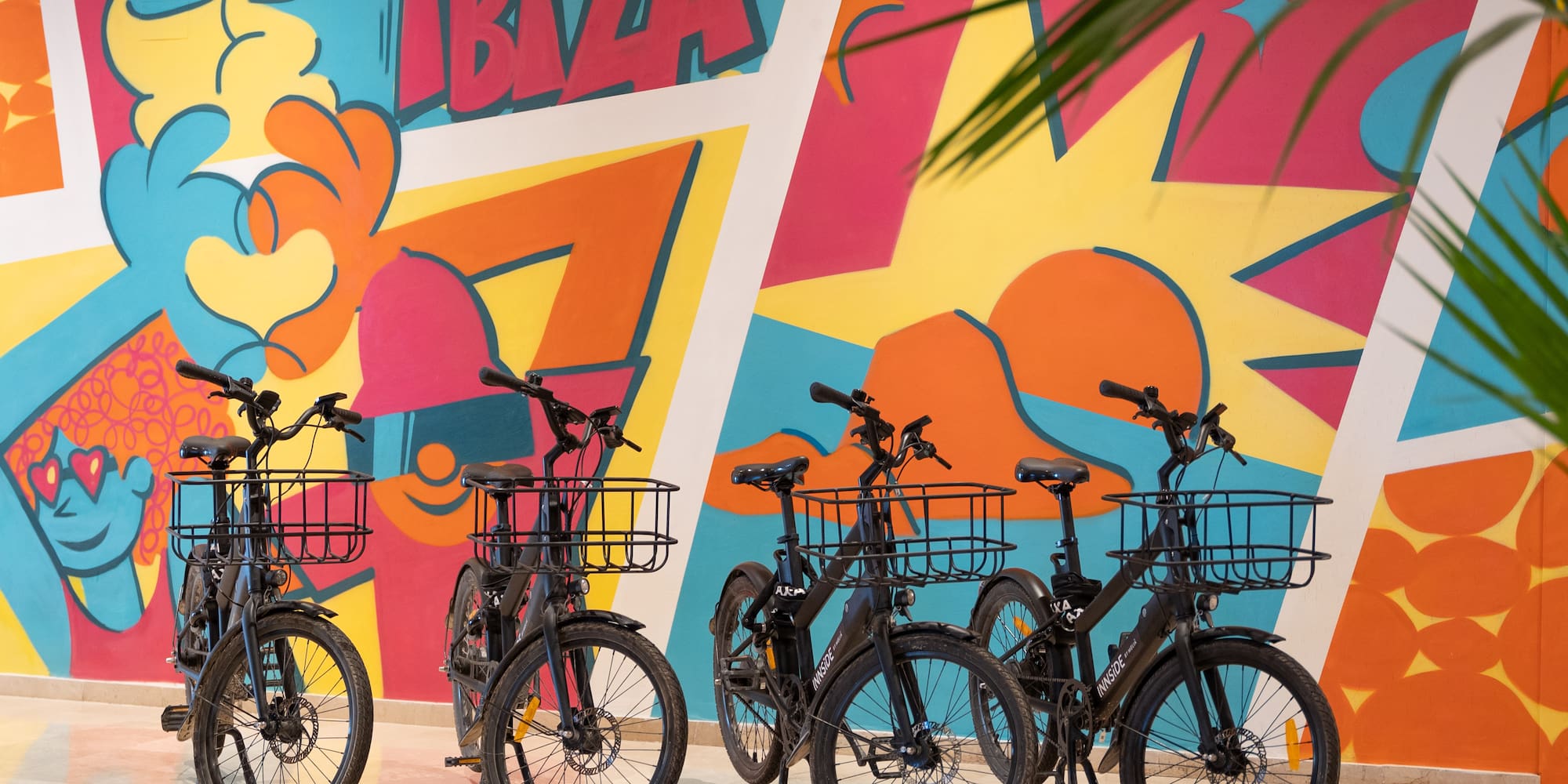 a group of bicycles with baskets in front of a colorful wall