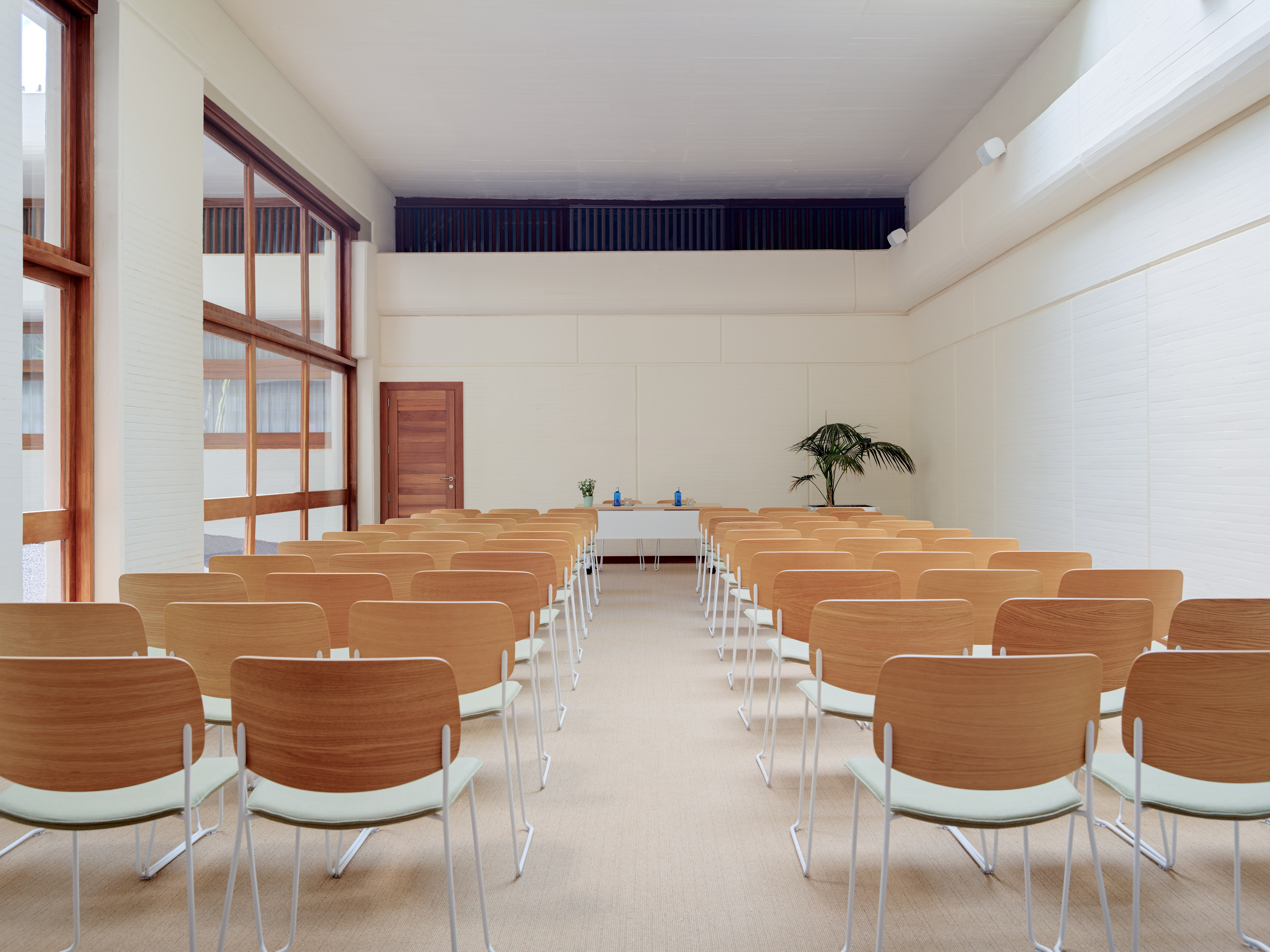 Modern conference room with light wood chairs, front table, and large windows.