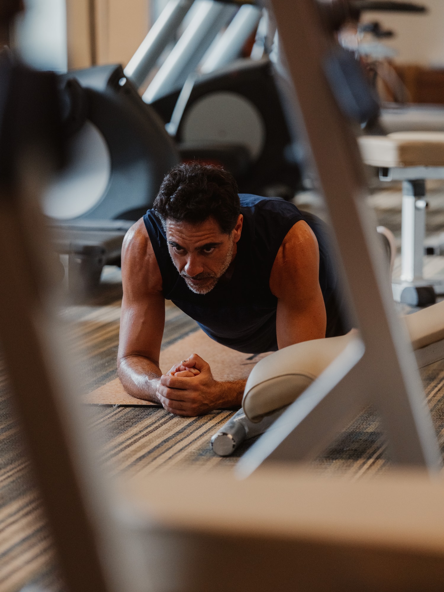 Hombre concentrado y sudoroso haciendo plancha en el gimnasio.