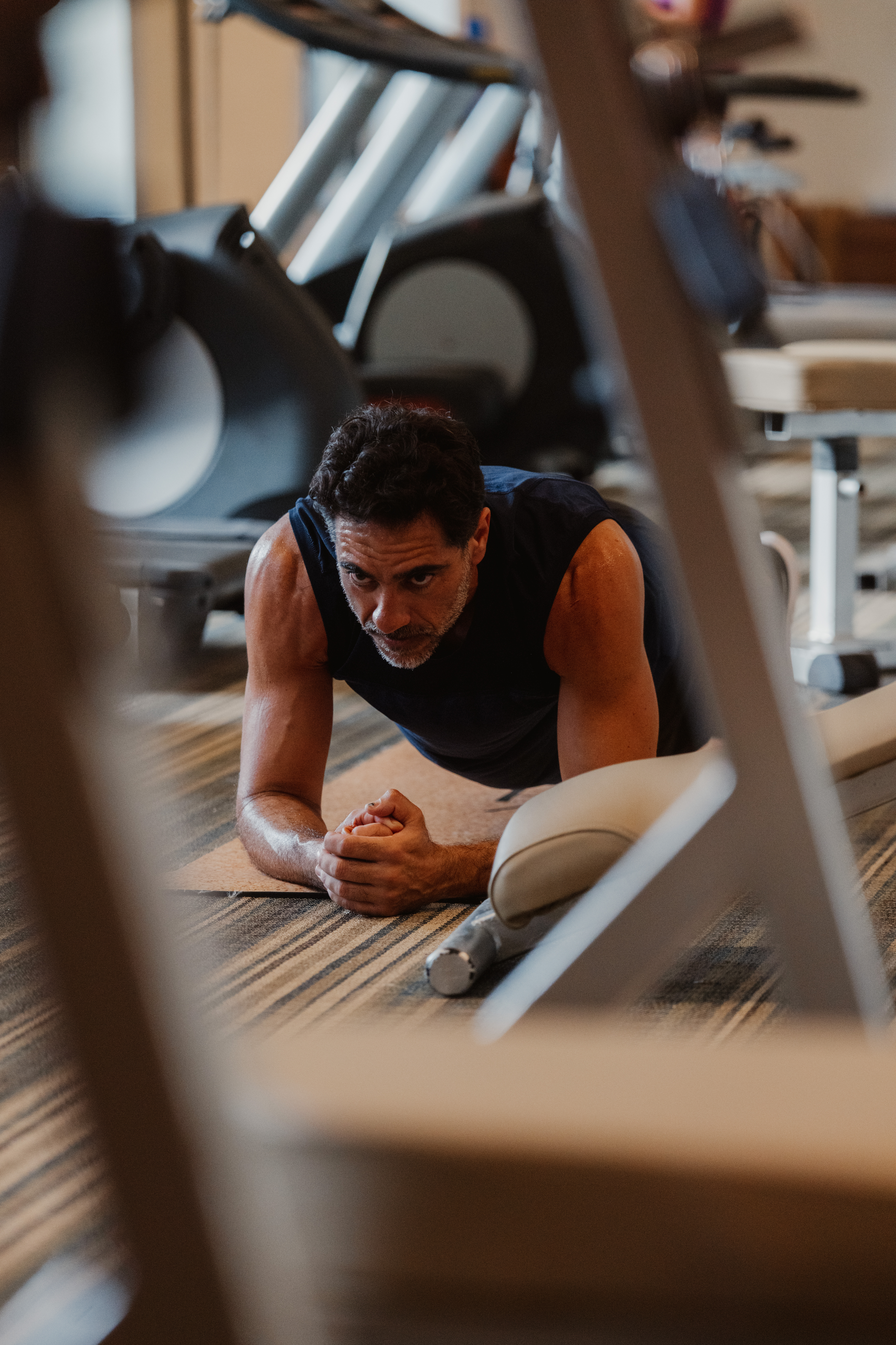 Hombre concentrado y sudoroso haciendo plancha en el gimnasio.