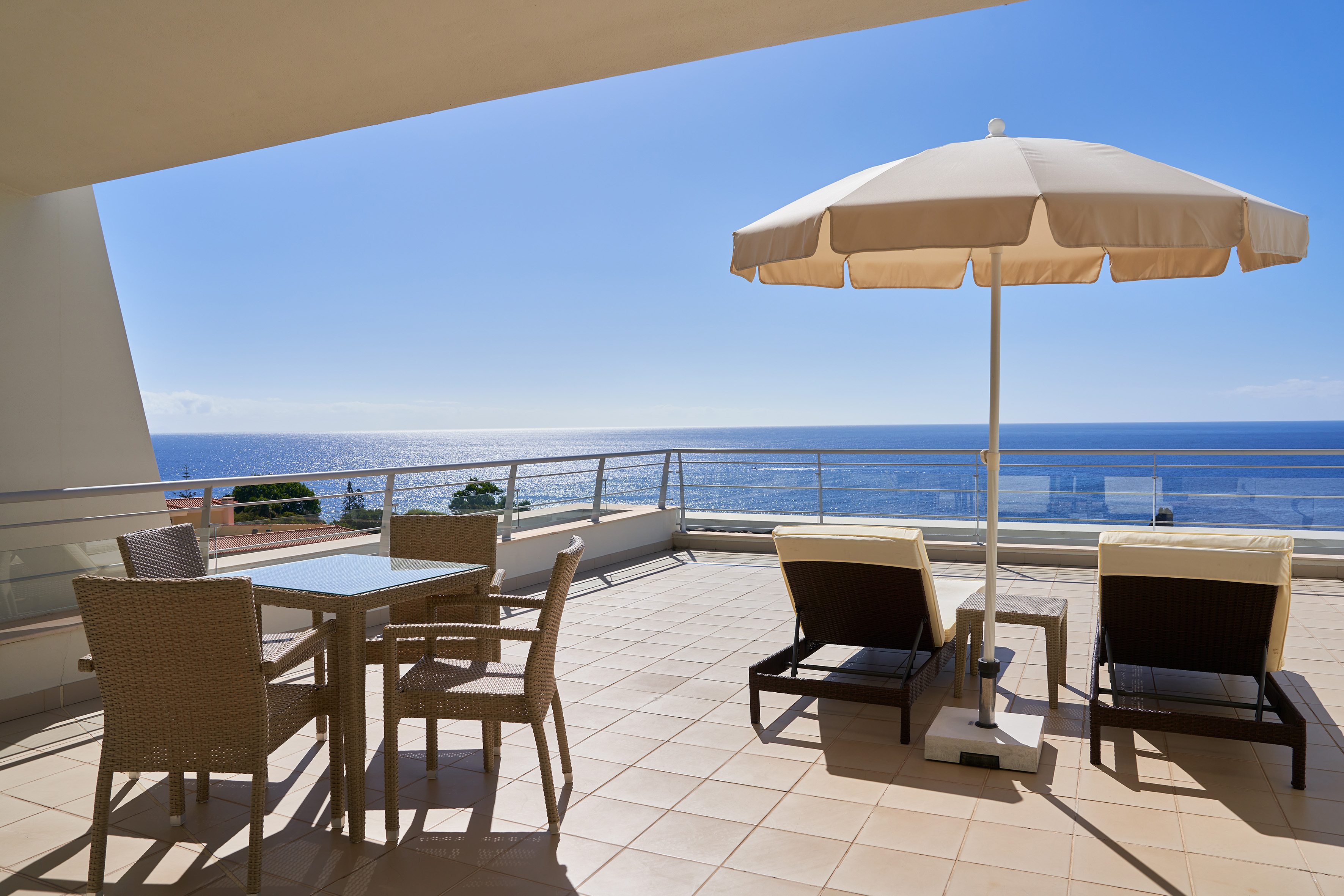 Ocean view balcony with patio dining set, lounge chairs, and sun umbrella.