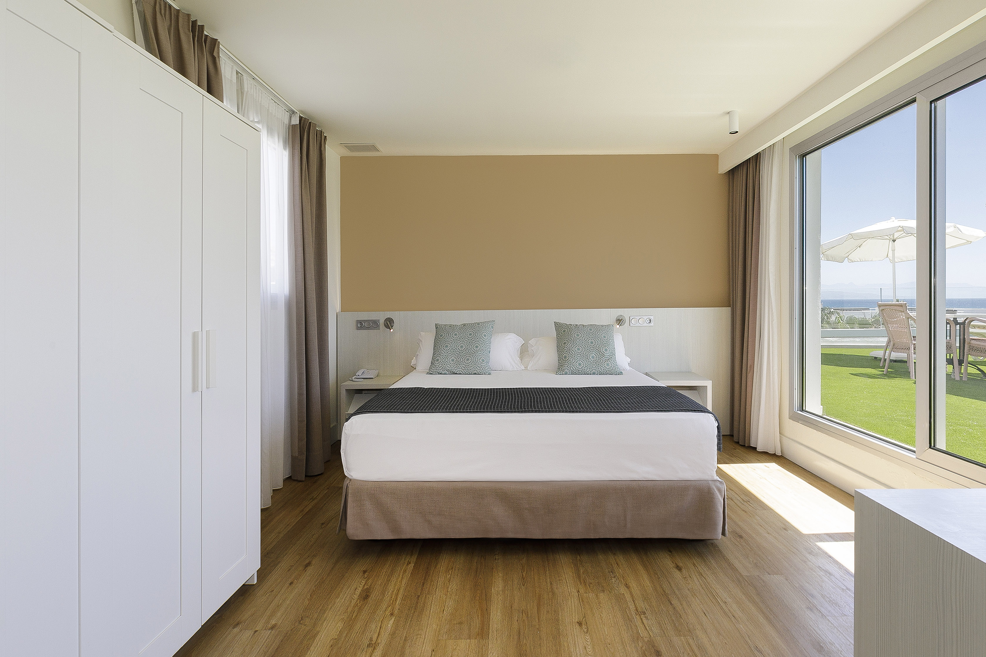 Modern resort bedroom with king bed and ocean view balcony.