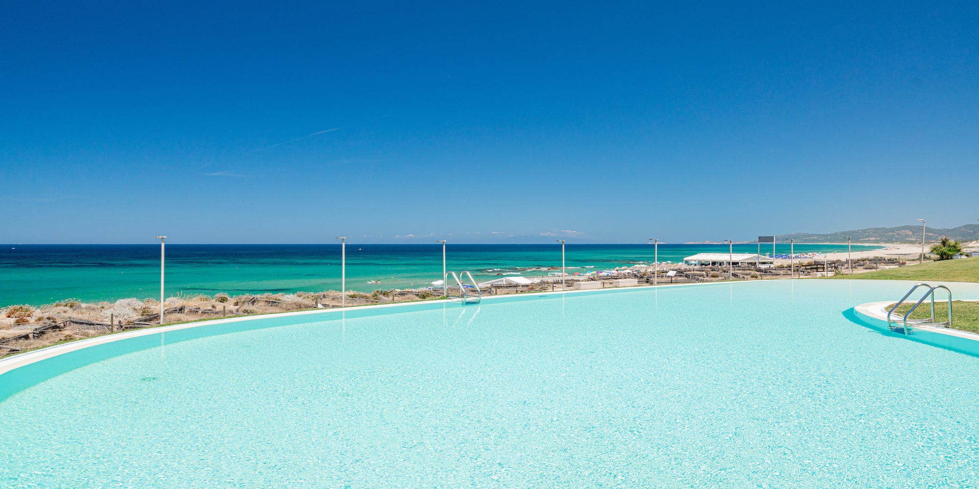 a large pool with a beach and blue sky
