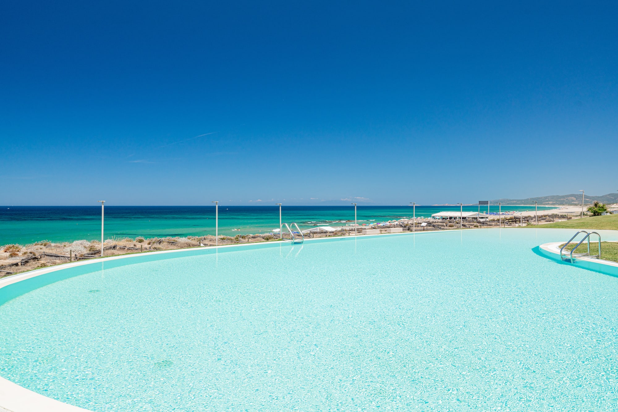a large pool with a beach and blue sky
