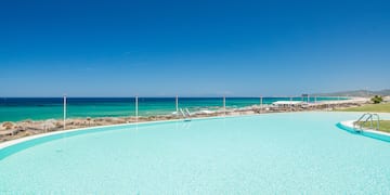 a large pool with a beach and blue sky