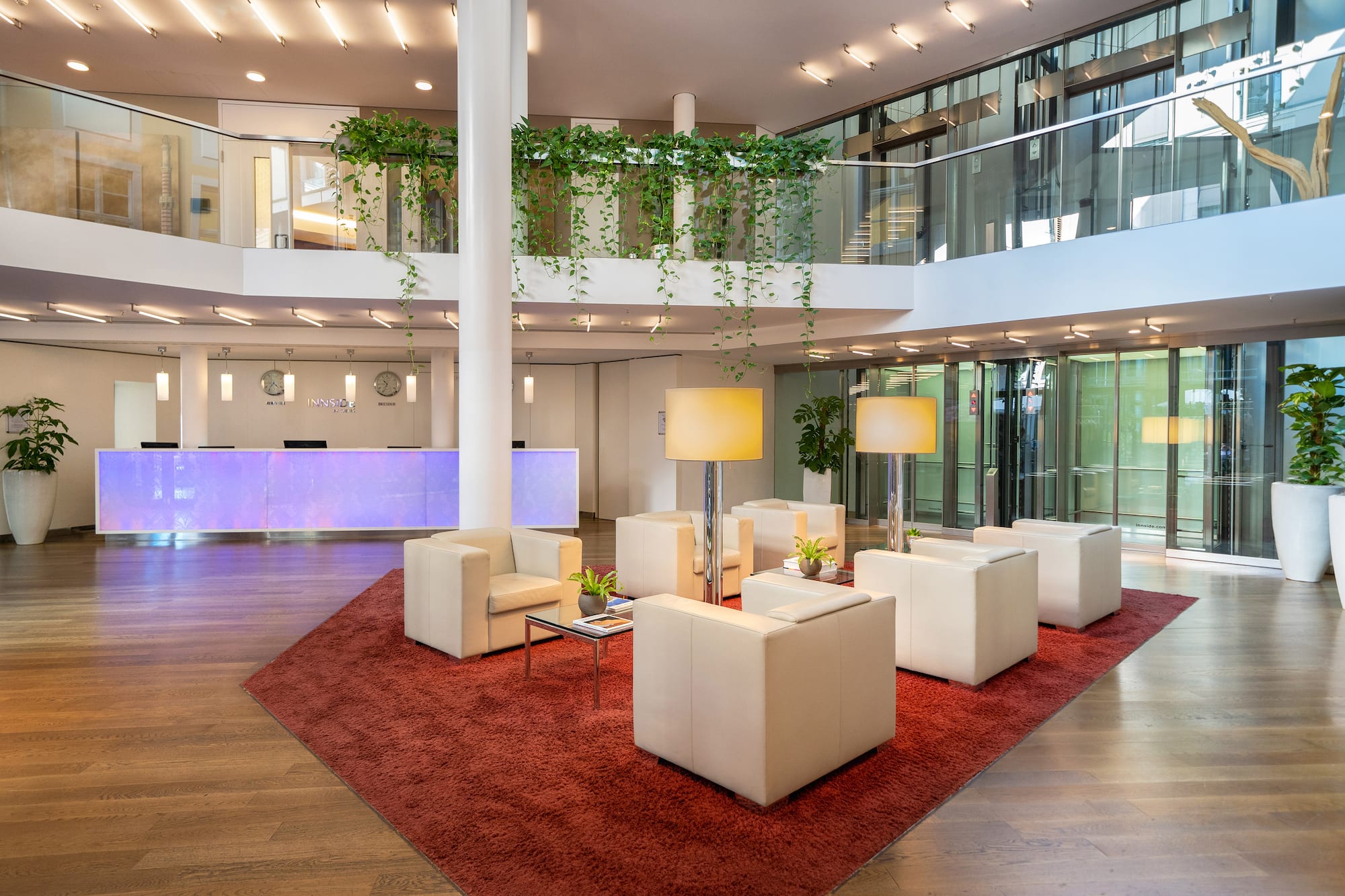 INNSIDE hotel lobby, modern lounge area, lit reception desk, green plants.