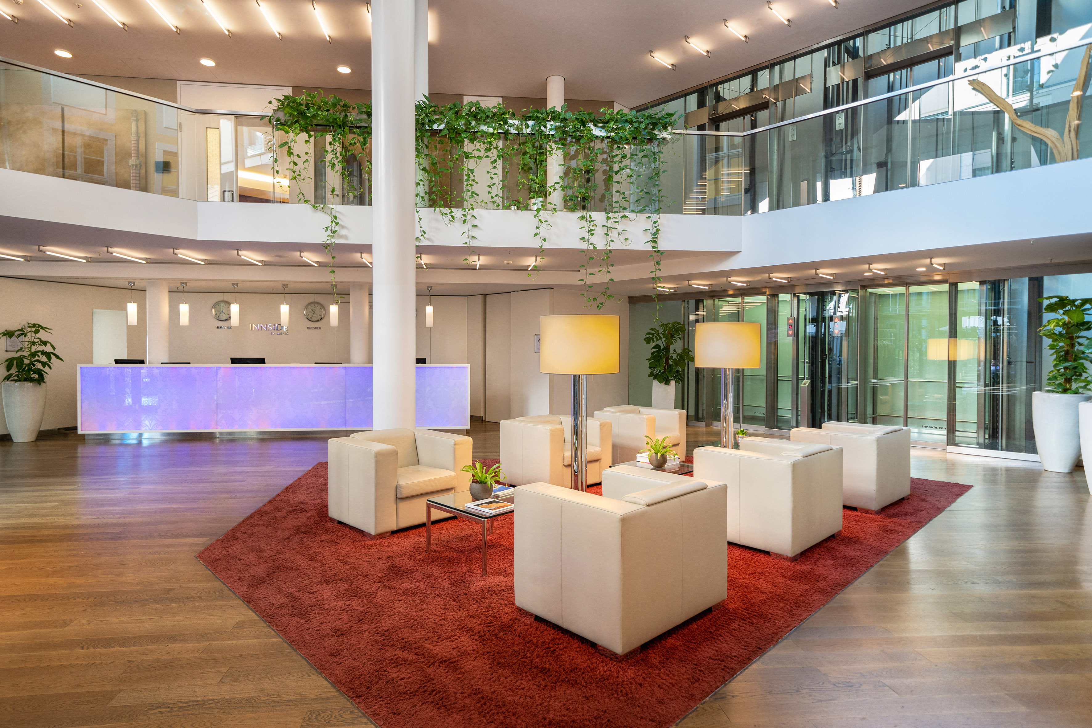 INNSIDE hotel lobby, modern lounge area, lit reception desk, green plants.