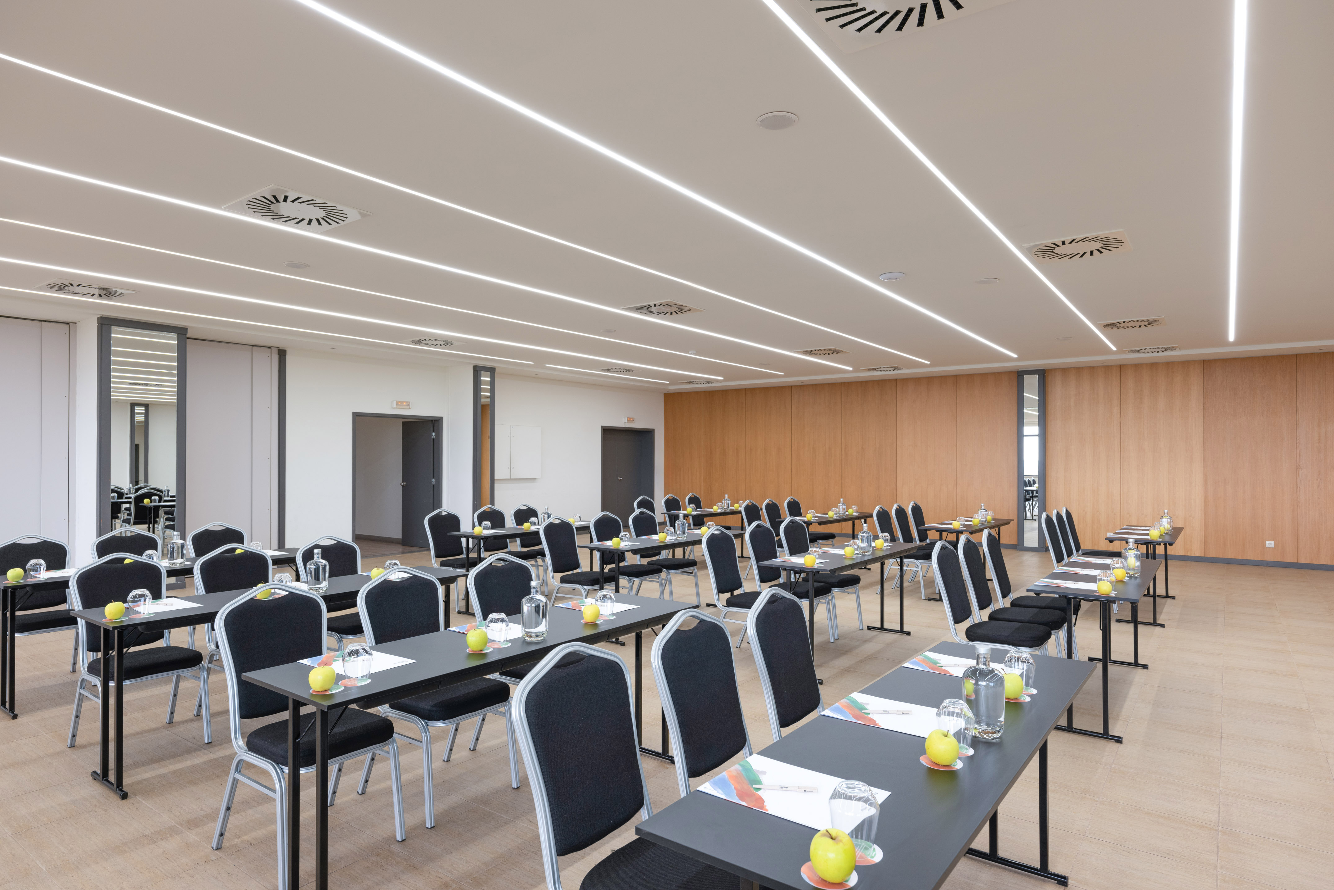 Modern corporate conference room with tables, chairs, and individual settings.