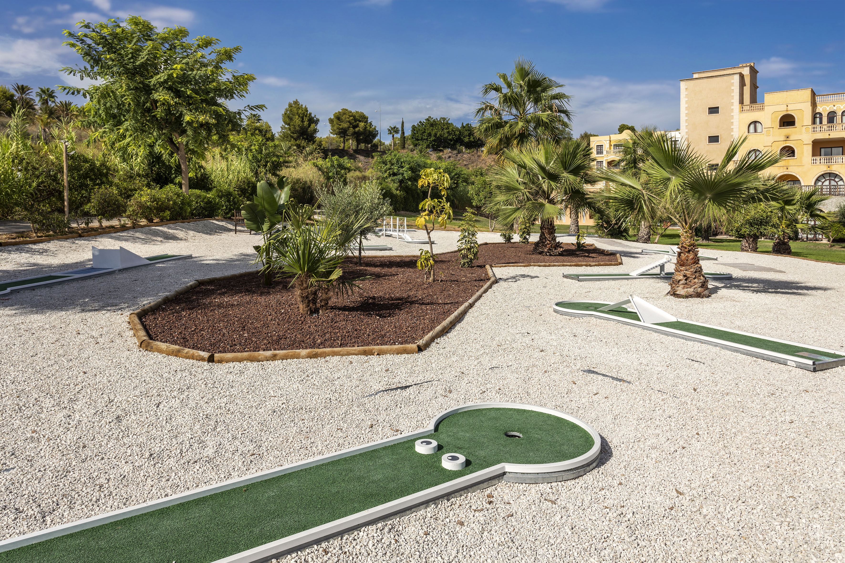 a mini golf course with palm trees and a building in the background